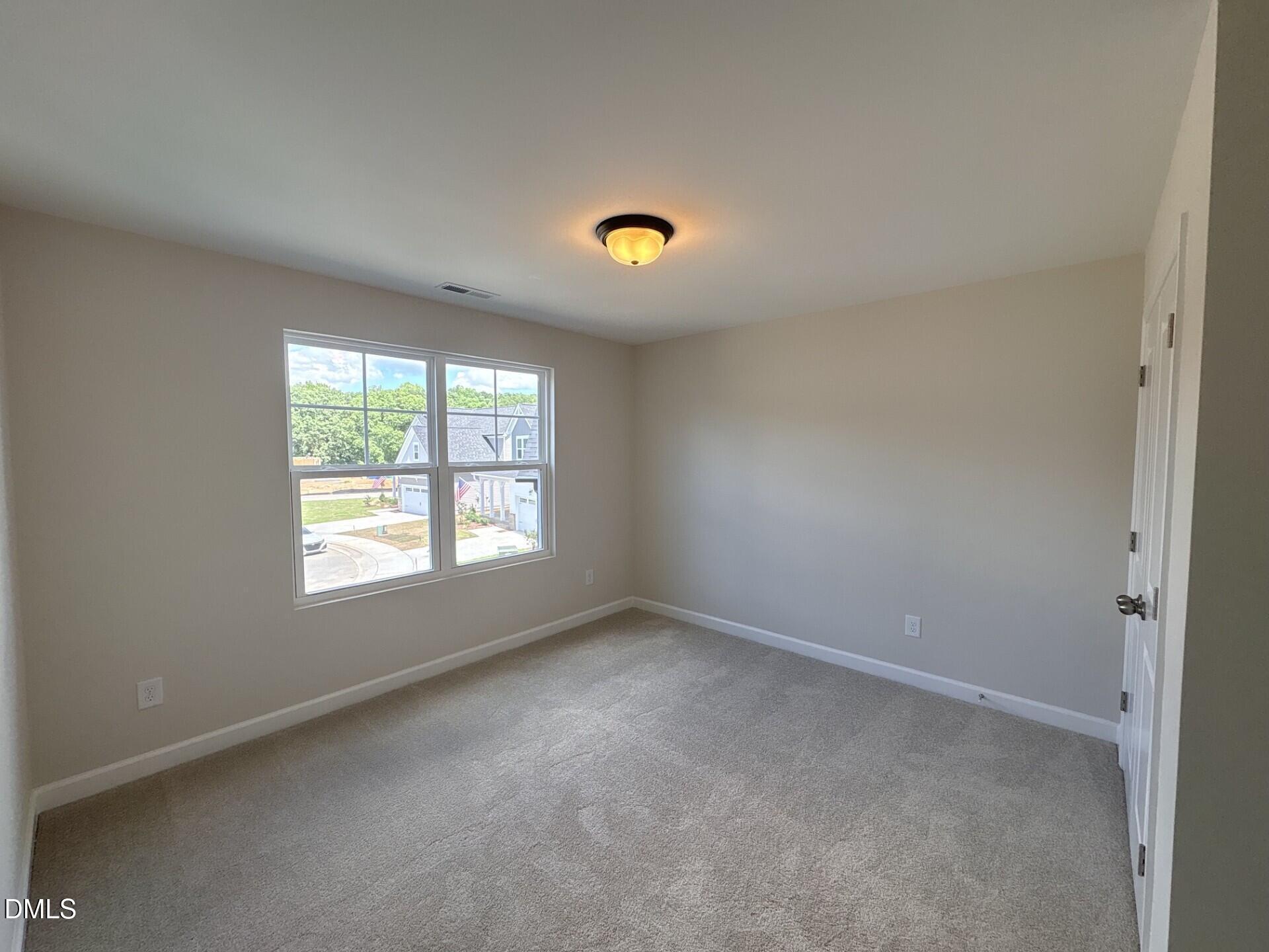 Spacious carpeted bedroom with neutral walls in The Ash C floor plan at Woodland Crossing, Zebulon, North Carolina.