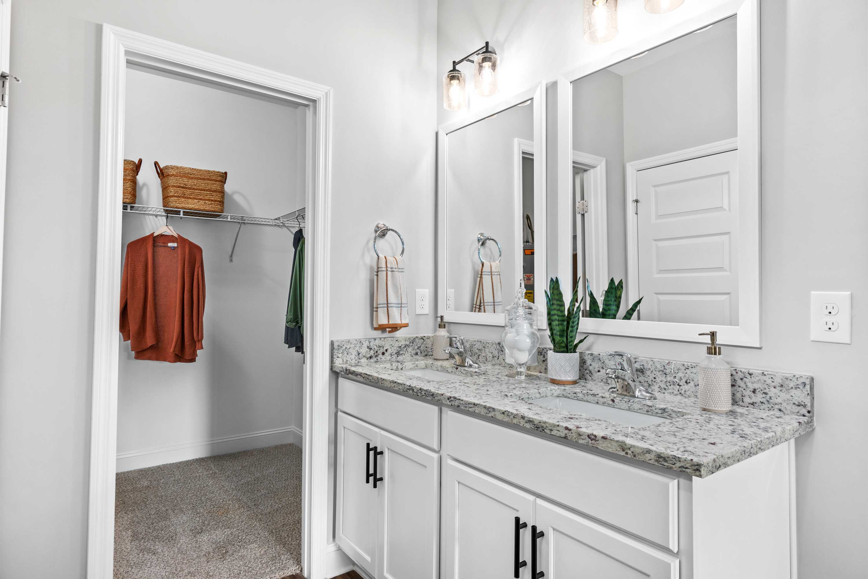 Modern primary bathroom at Wood Trail in Toney Alabama with double vanity, quartz countertop, and open walk-in closet