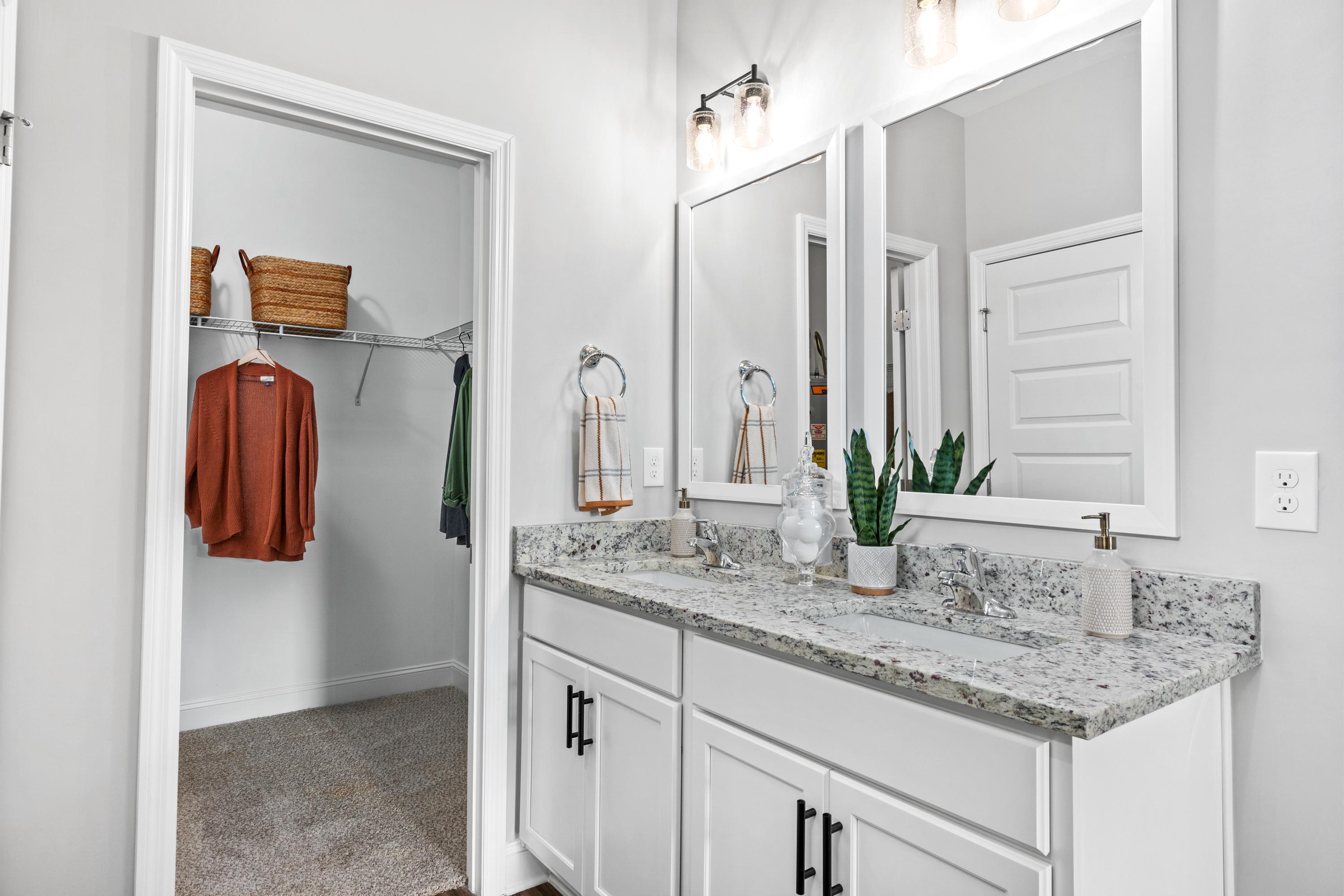 Modern primary bathroom at Wood Trail in Toney Alabama with double vanity, quartz countertop, and open walk-in closet