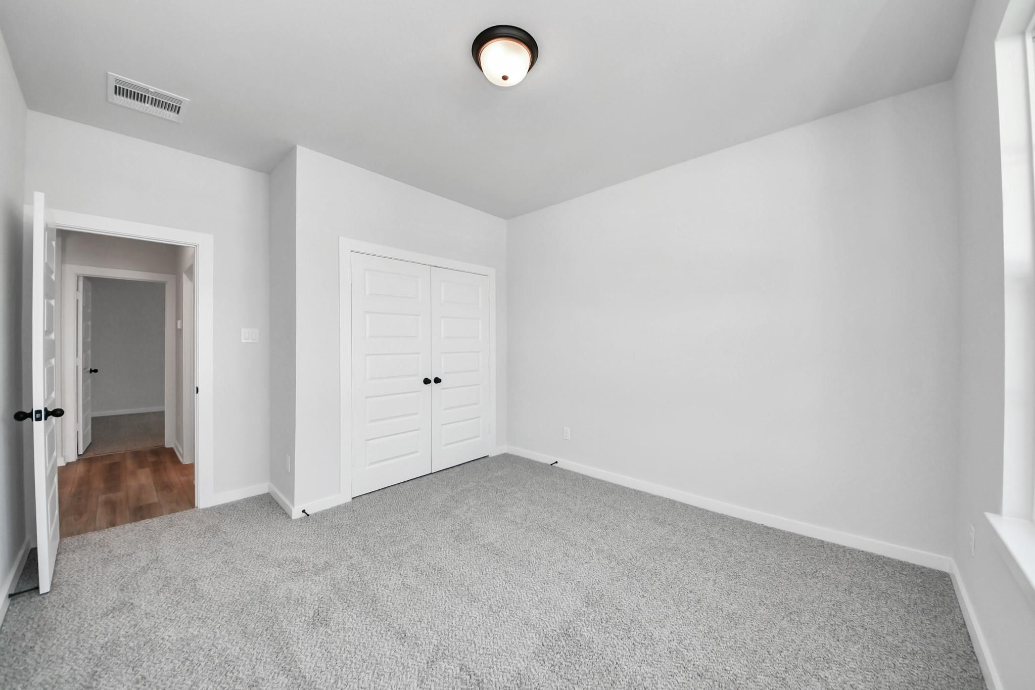 Spacious secondary bedroom with plush carpet and double-door closet in The Everett C floor plan, River Ranch Meadows, Dayton.