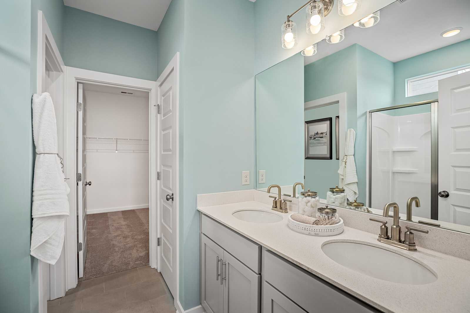 Spacious primary bathroom at Sage Farms in White House TN with double vanity, glass shower, and light blue walls