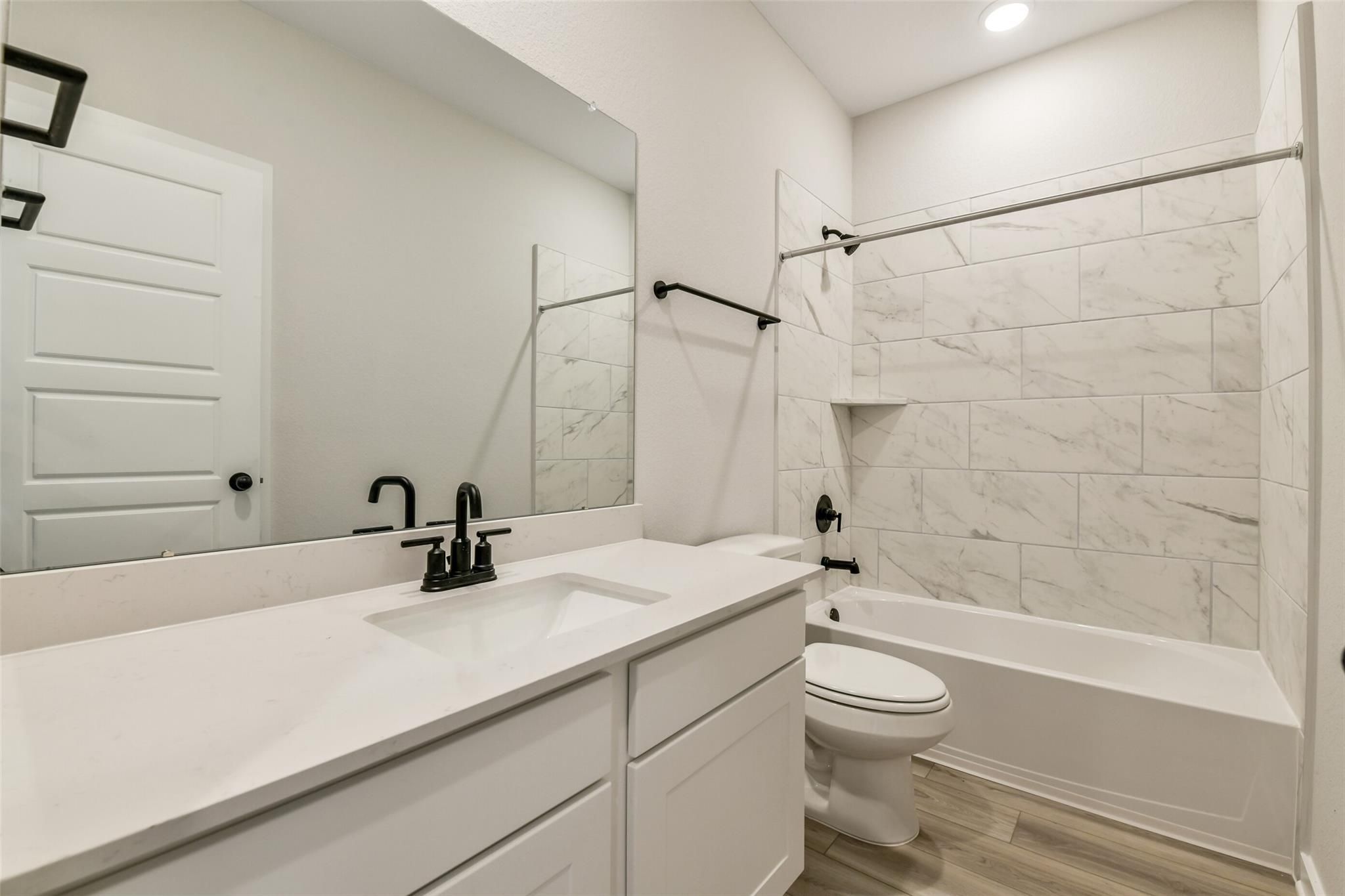Modern secondary bathroom with white quartz vanity, subway tile shower-tub combo in Davidson Homes The Daphne H, Crosby, Texas