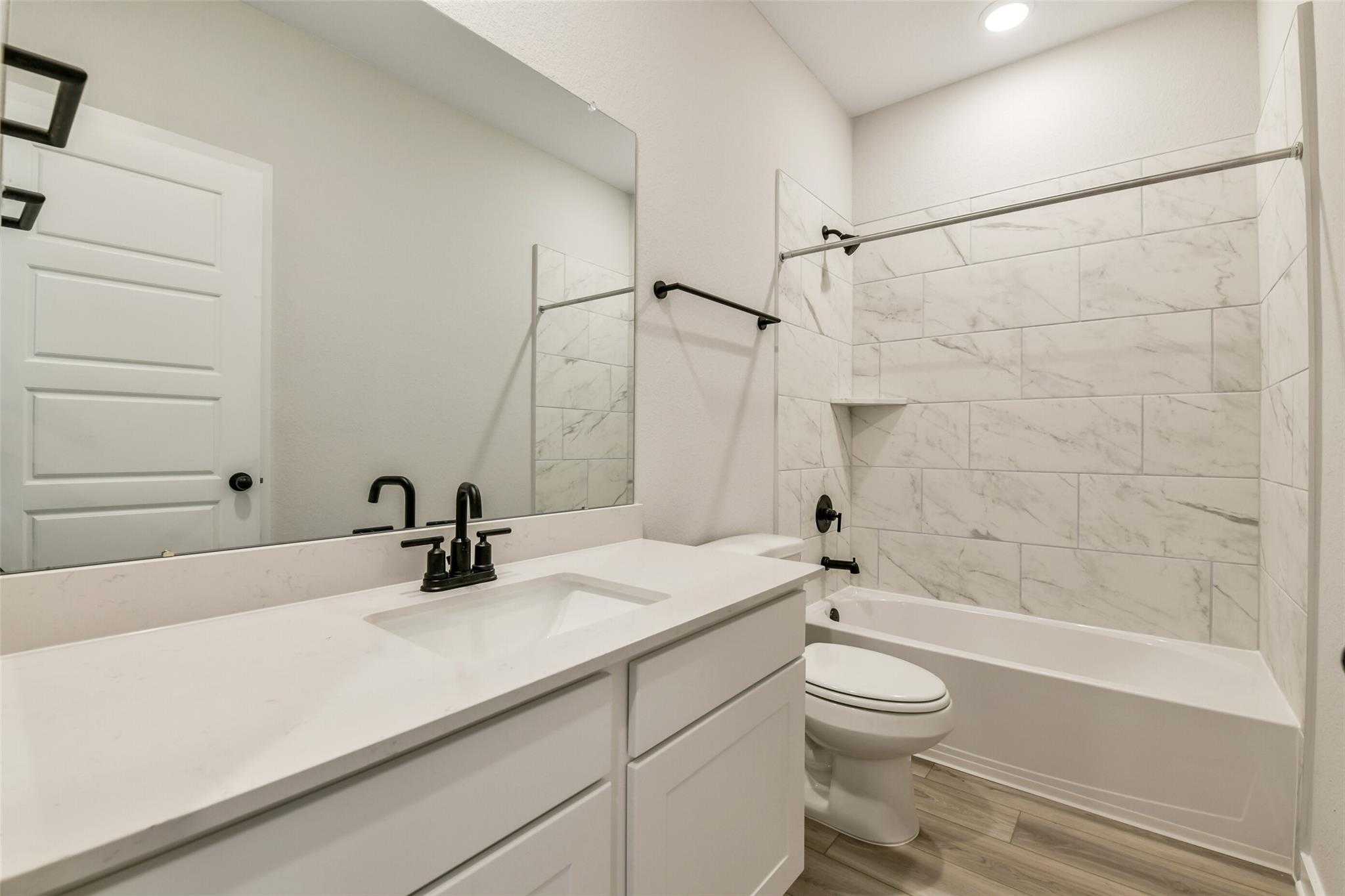 Modern secondary bathroom with white quartz vanity, subway tile shower-tub combo in Davidson Homes The Daphne H, Crosby, Texas