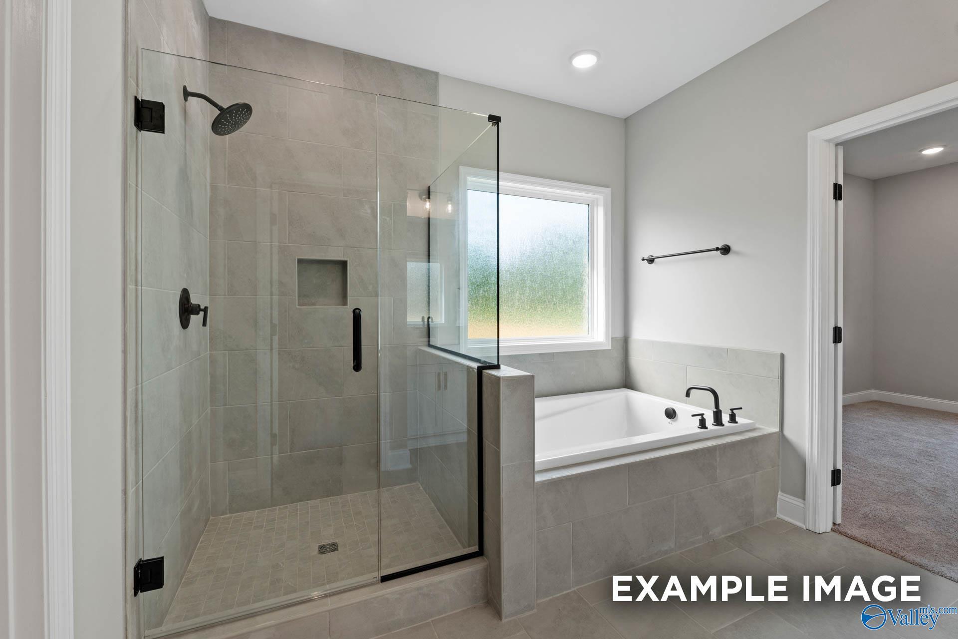 Modern primary bathroom with glass-enclosed shower and soaking tub in The Montgomery B plan at The Meadows, Athens, Alabama.