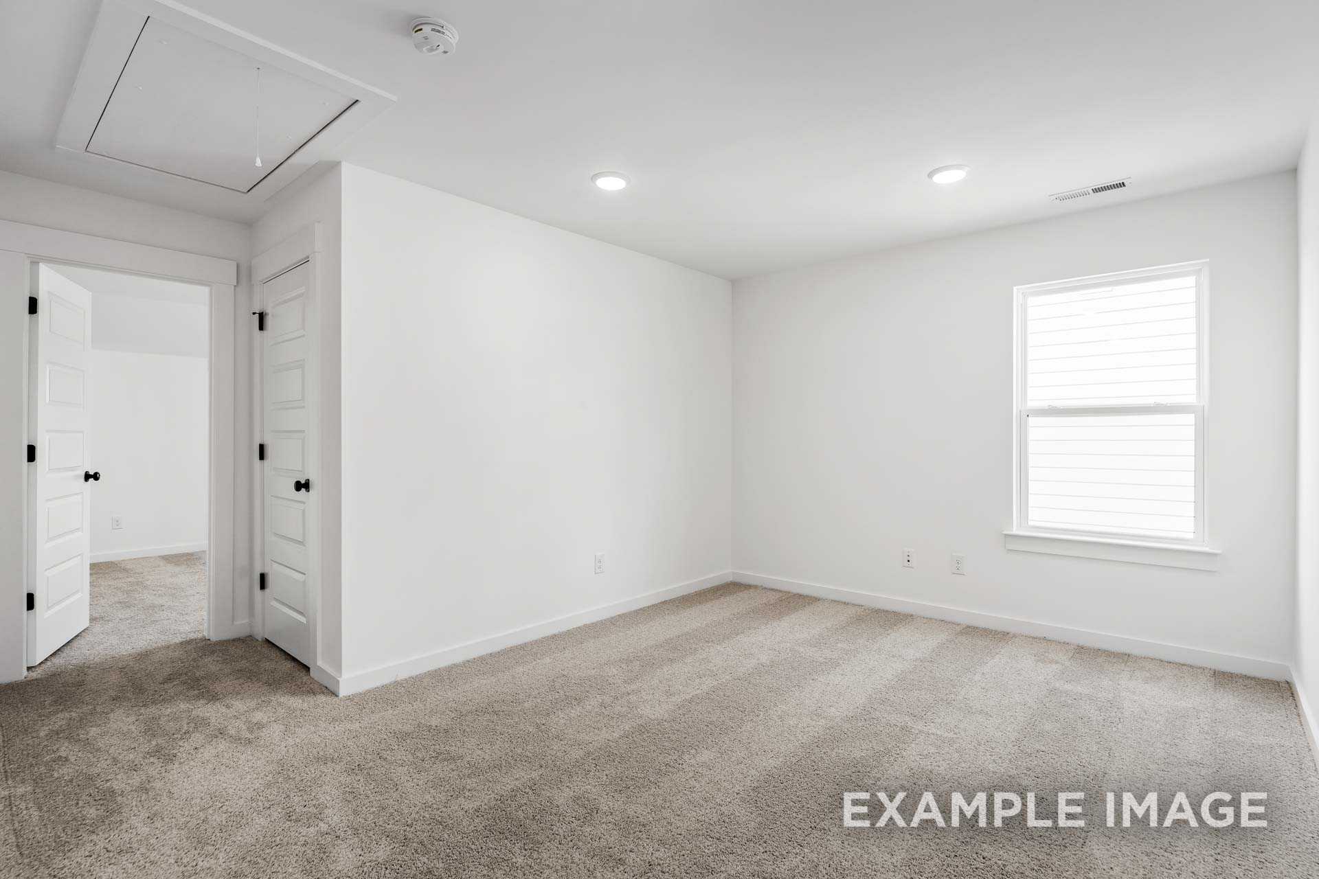 Spacious bedroom in The Ashcroft plan featuring white walls, beige carpet, double entry doors, and large window with blinds