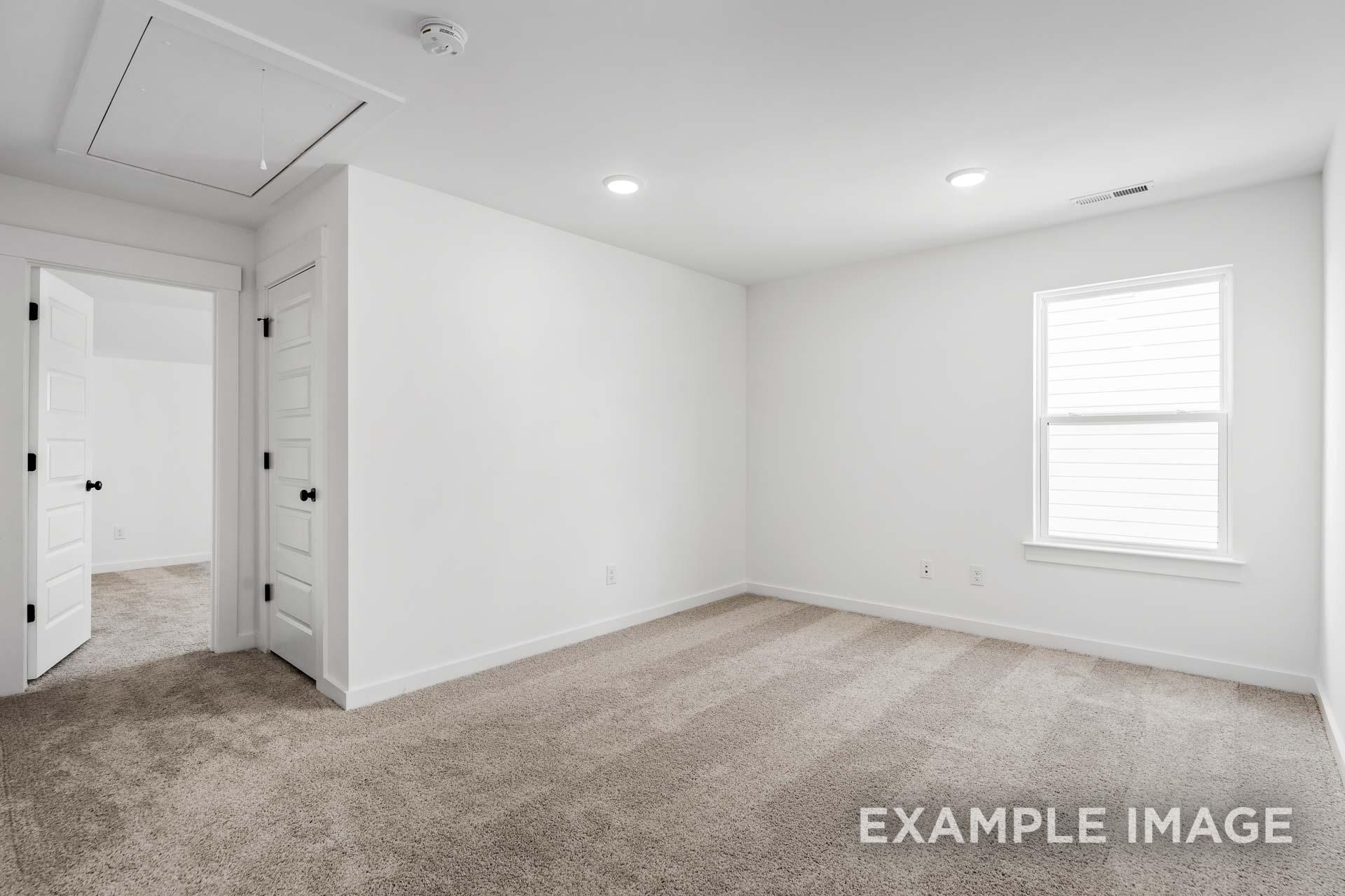Spacious bedroom in The Ashcroft plan featuring white walls, beige carpet, double entry doors, and large window with blinds