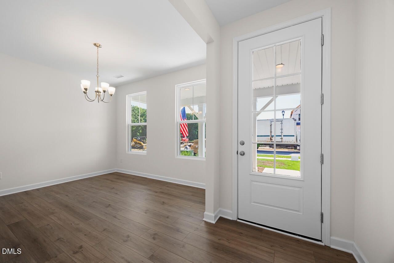 Bright foyer with glass-panel front door, luxury vinyl plank flooring, and chandelier in Davidson Homes Willow B plan, Zebulon NC
