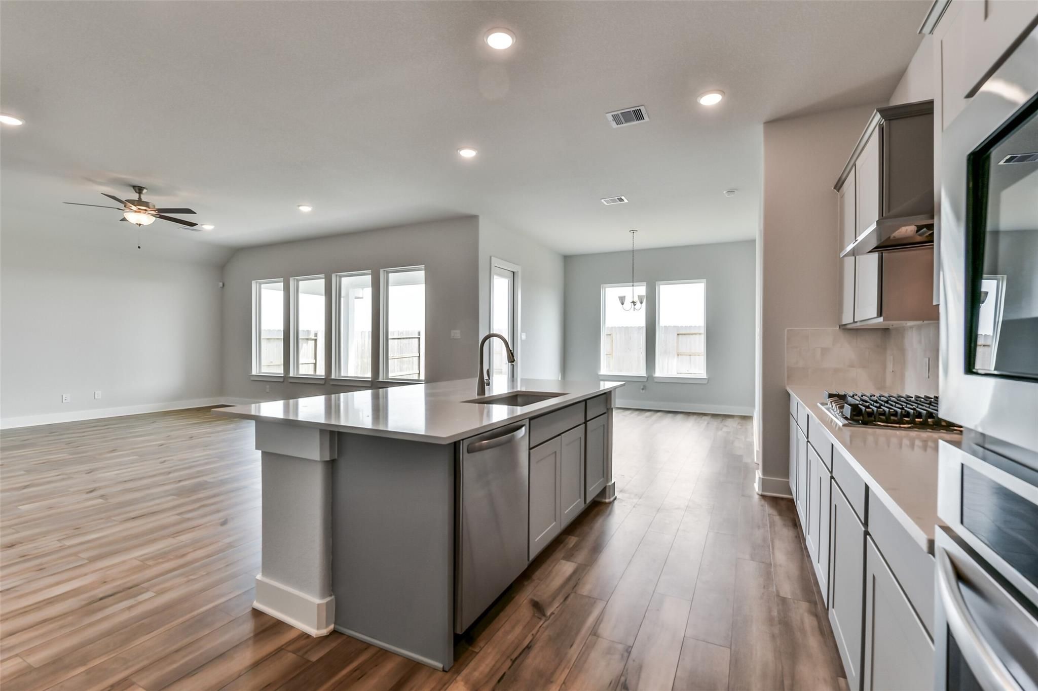 Modern open-concept kitchen featuring gray quartz island, stainless steel appliances, and large windows in Davidson Homes The George A, Lago Mar