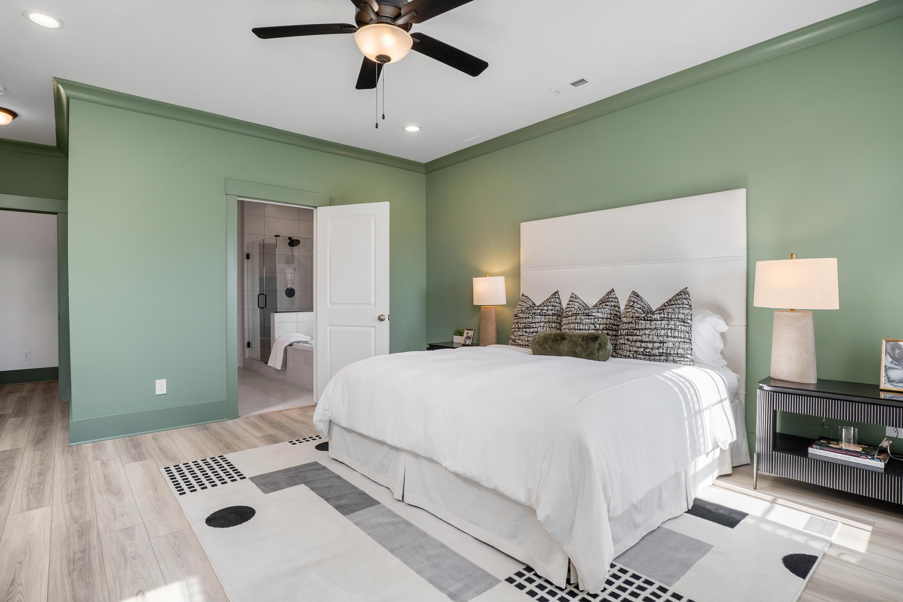 Spacious master bedroom at Barnett's Crossing in Madison AL with sage green walls, king bed, ceiling fan, and en-suite bath