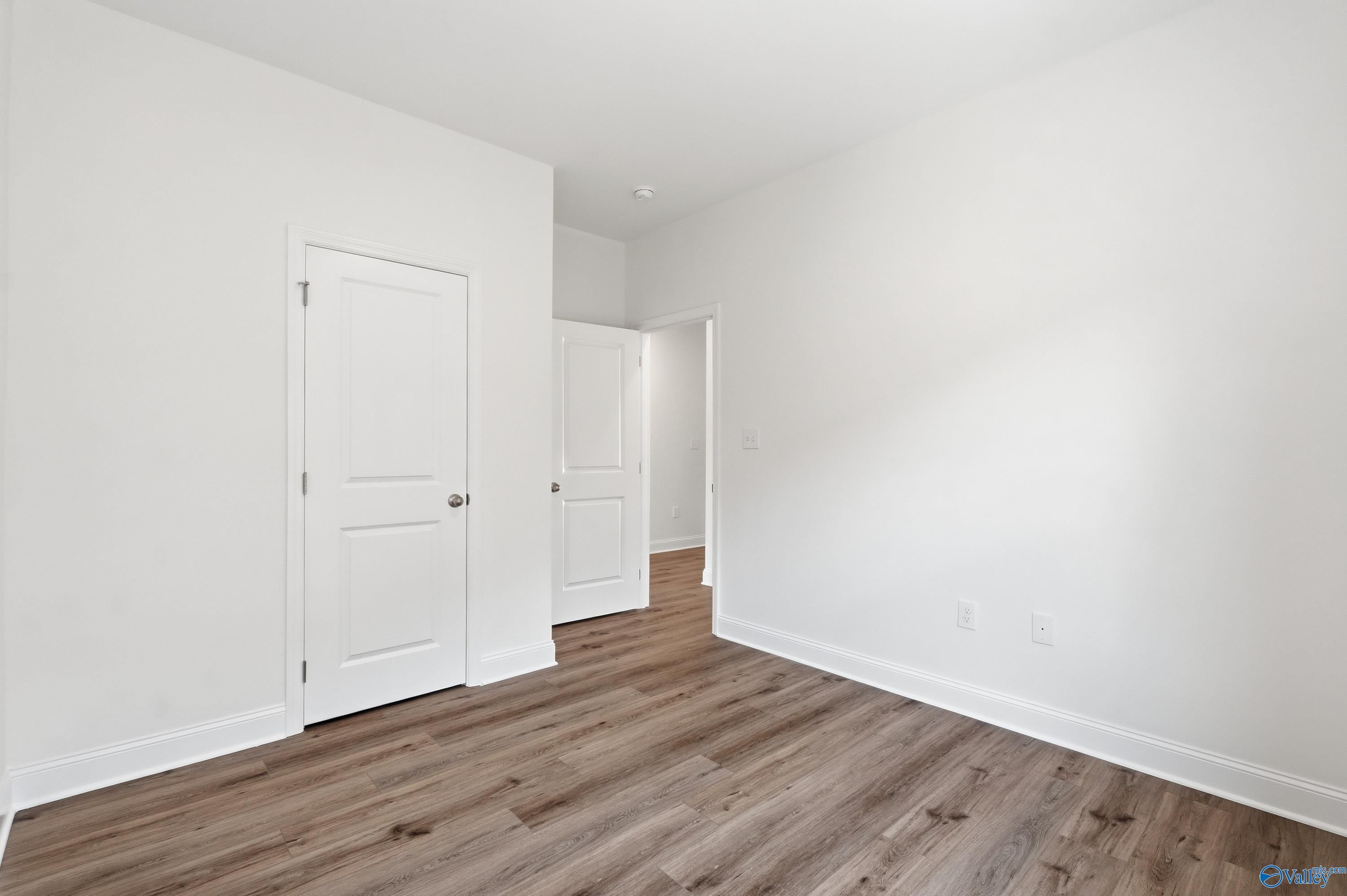 Bright secondary bedroom with wood-look flooring in The Asheville floor plan at Jaguar Hills in Huntsville, Alabama.