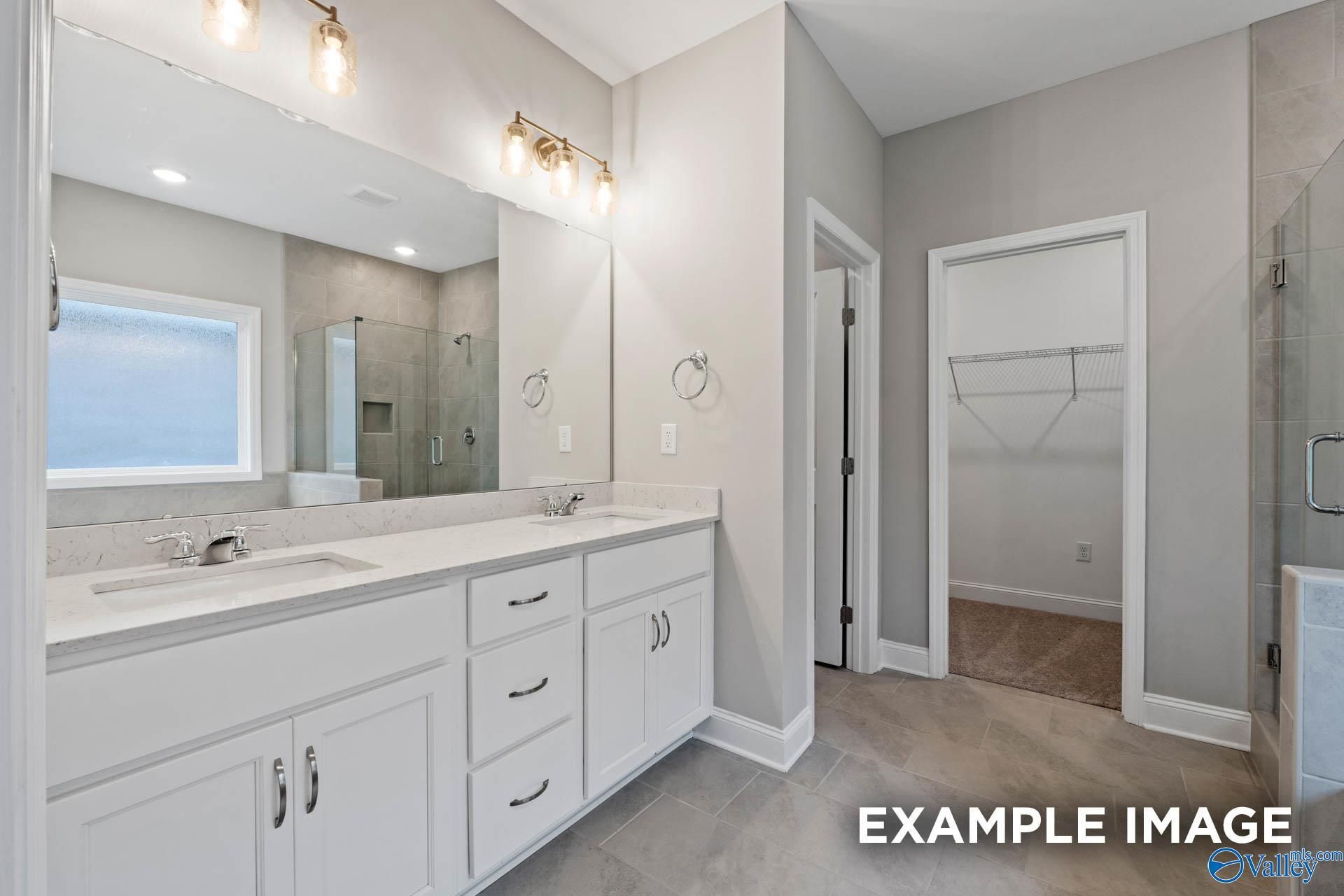 Modern master bathroom featuring double vanity, frameless glass shower, and walk-in closet in Davidson Homes The Montgomery, Meridianville, AL