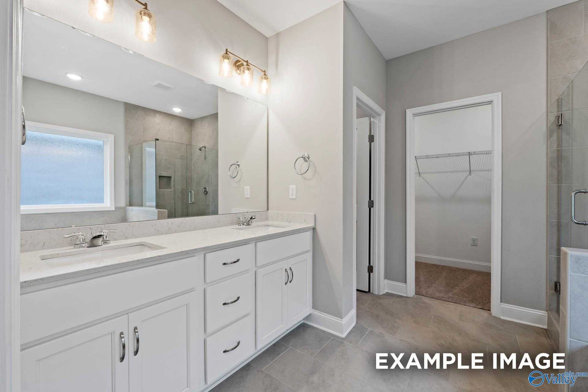Modern master bathroom featuring double vanity, frameless glass shower, and walk-in closet in Davidson Homes The Montgomery, Meridianville, AL