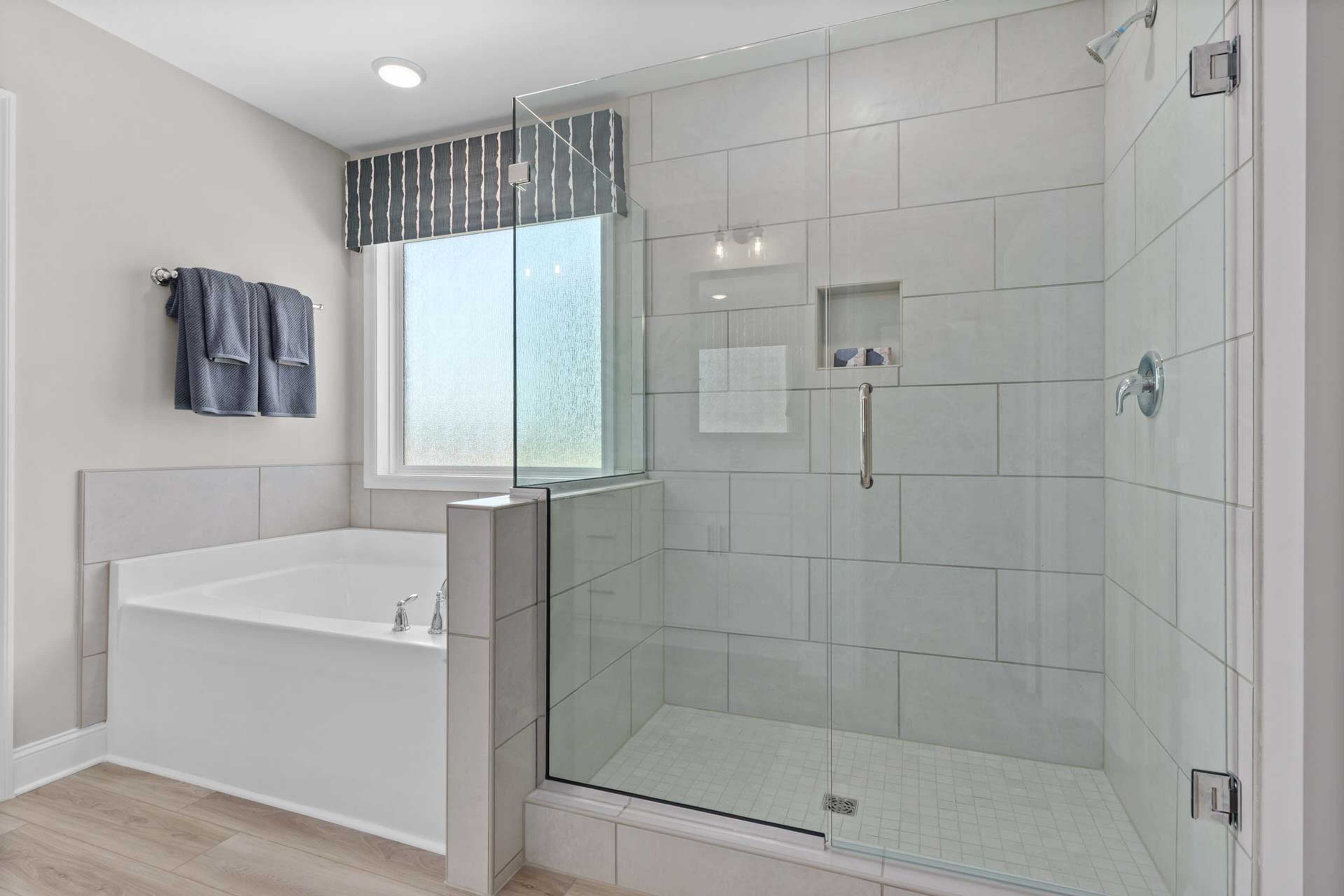 Spacious modern bathroom at Creek Grove in New Market, Alabama with frameless glass shower, soaking tub, subway tile and window