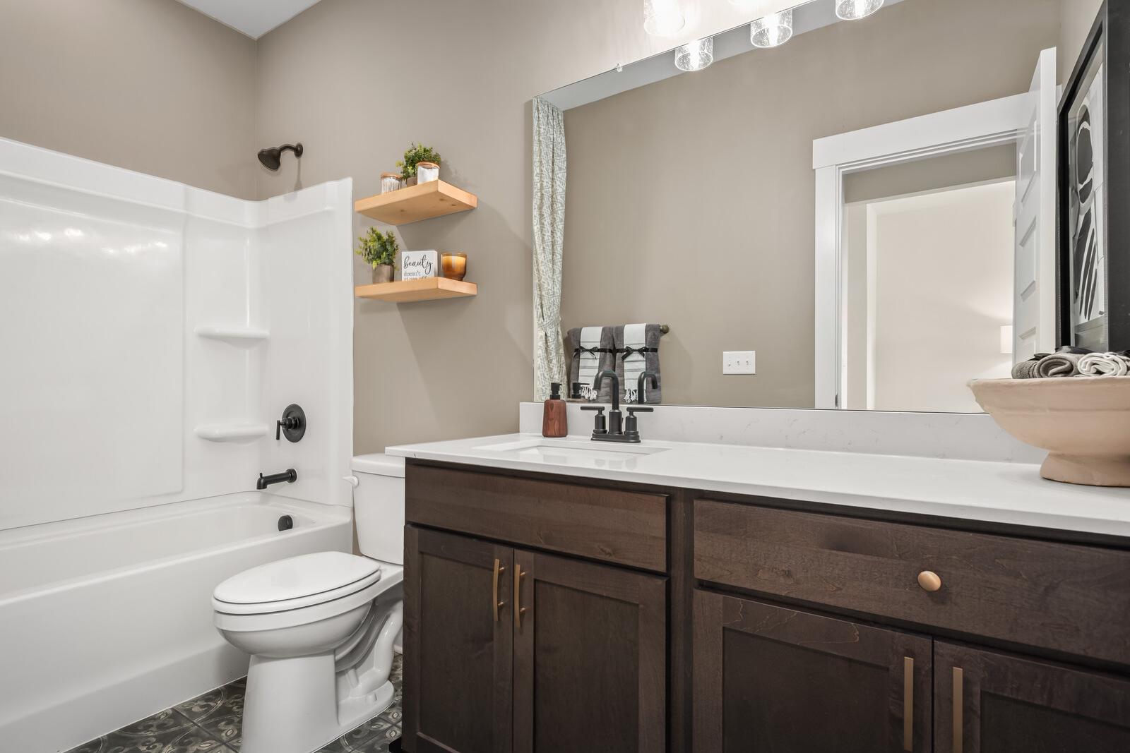 Spacious master bathroom in The Ridgeport by Davidson Homes featuring white tub-shower combo, wood vanity, and neutral tones
