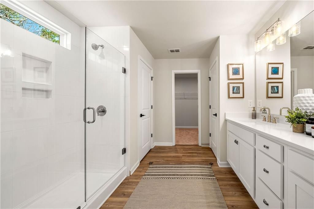 Modern master bathroom with frameless glass shower, double vanity, and walk-in closet in Davidson Homes The Willow B, Dallas, GA
