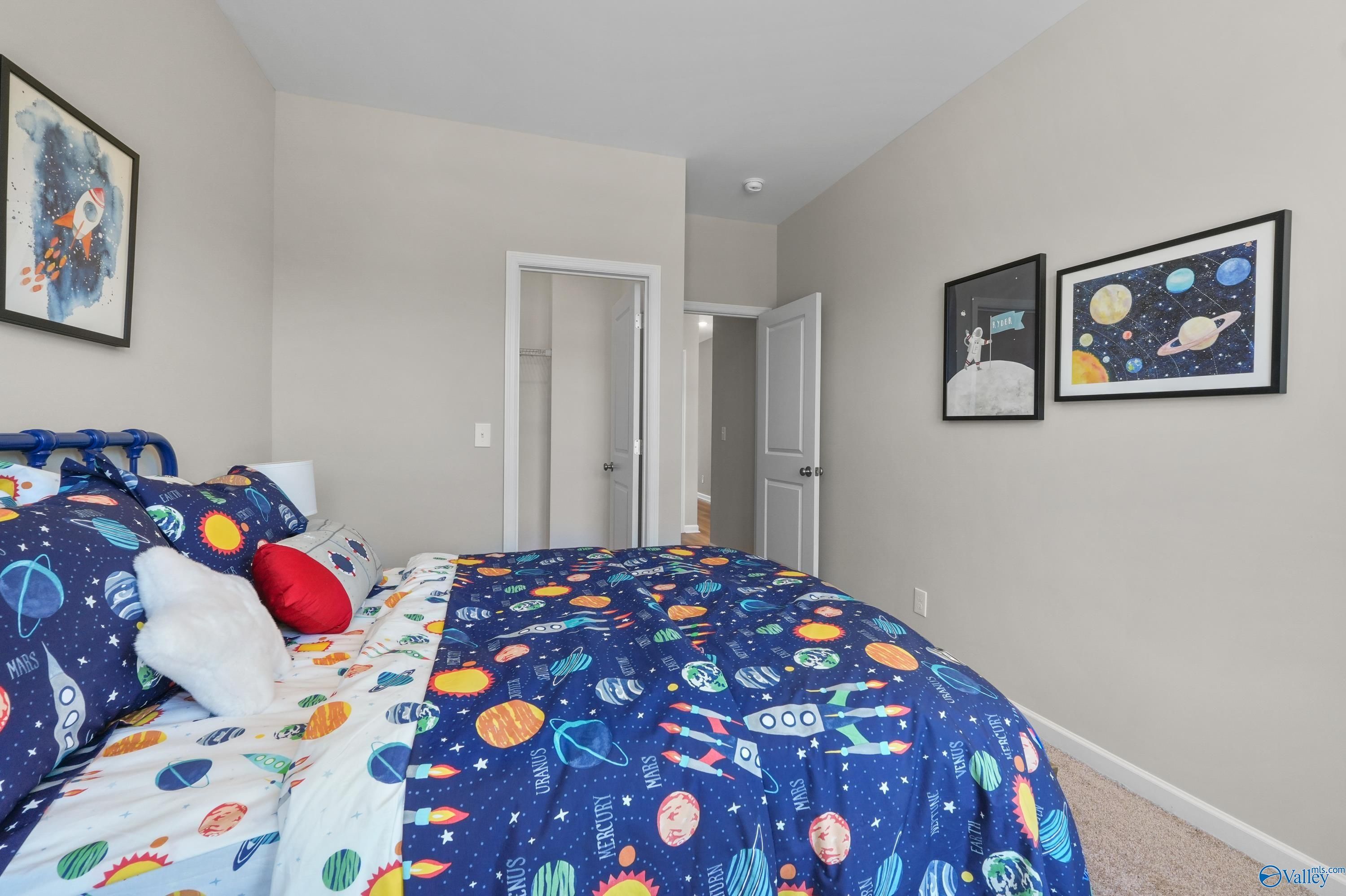 Cozy space-themed child's bedroom with rocket bedding, starry pillows and posters in Evermore Homes The Malibu, Madison, Alabama