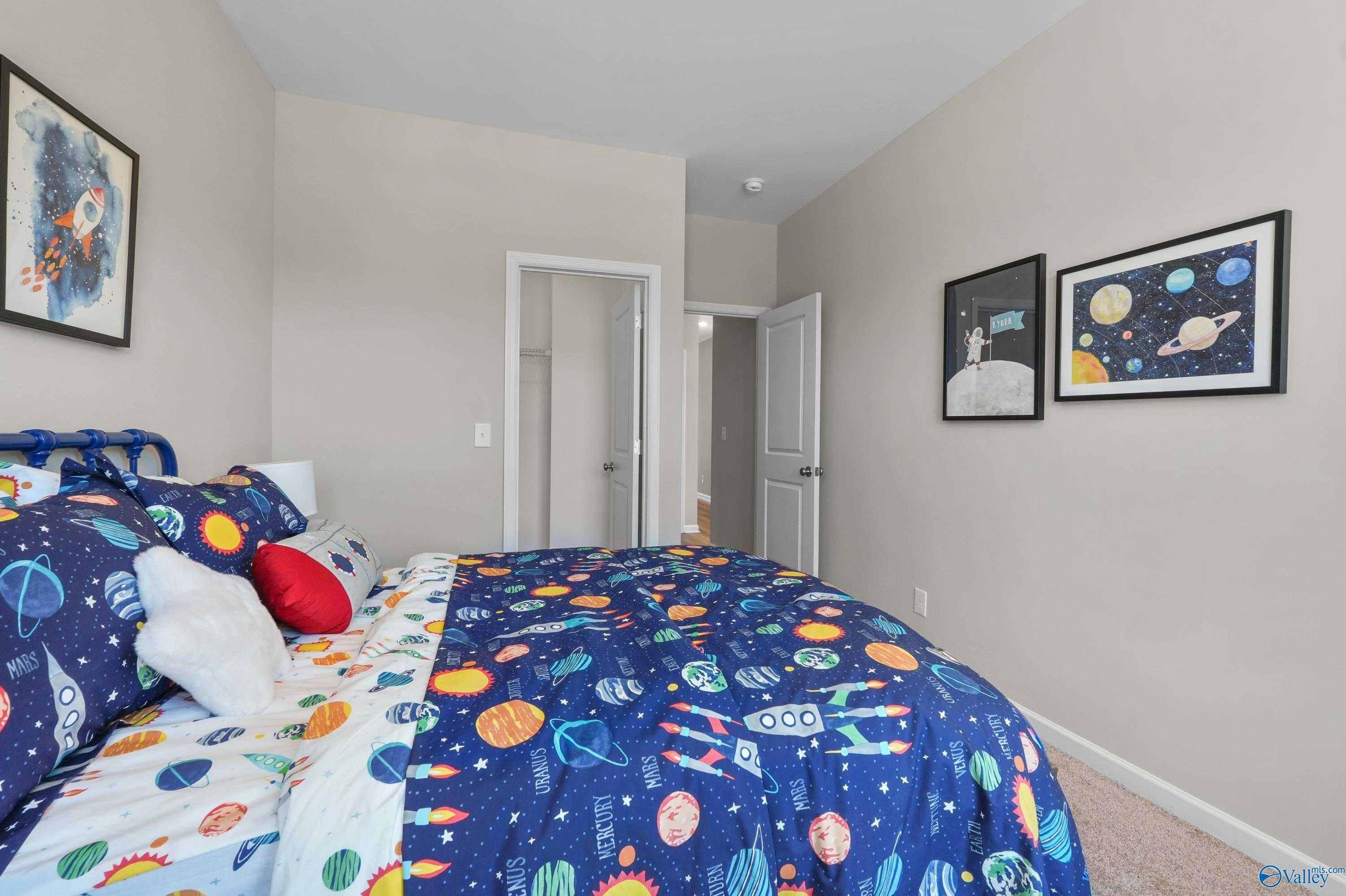 Cozy space-themed child's bedroom with rocket bedding, starry pillows and posters in Evermore Homes The Malibu, Madison, Alabama