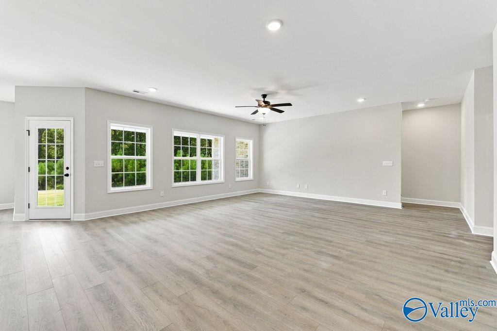 Bright open-concept living room with luxury vinyl plank flooring, ceiling fan, and natural light in Davidson Homes Rockford, Hartselle AL