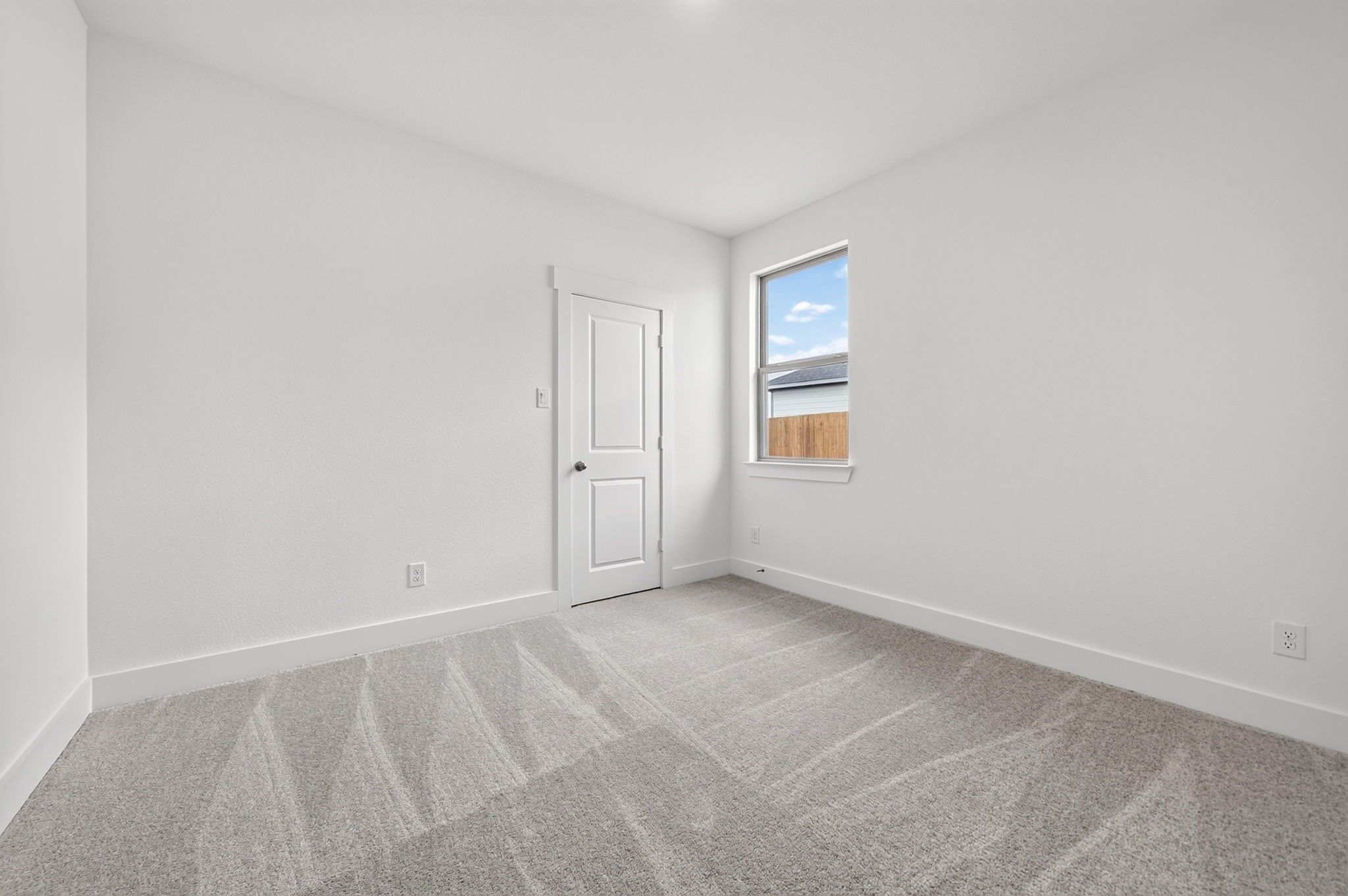 Bright empty bedroom with carpet, white walls, and window overlooking fenced backyard in Davidson Homes Holly F plan, Josephine, TX