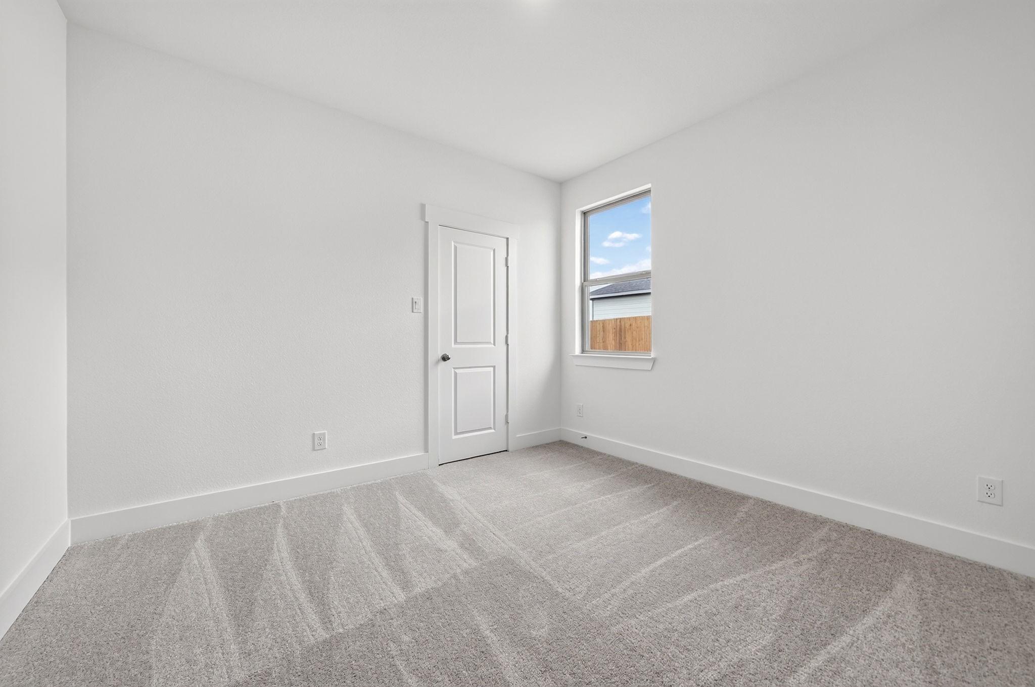 Bright empty bedroom with carpet, white walls, and window overlooking fenced backyard in Davidson Homes Holly F plan, Josephine, TX