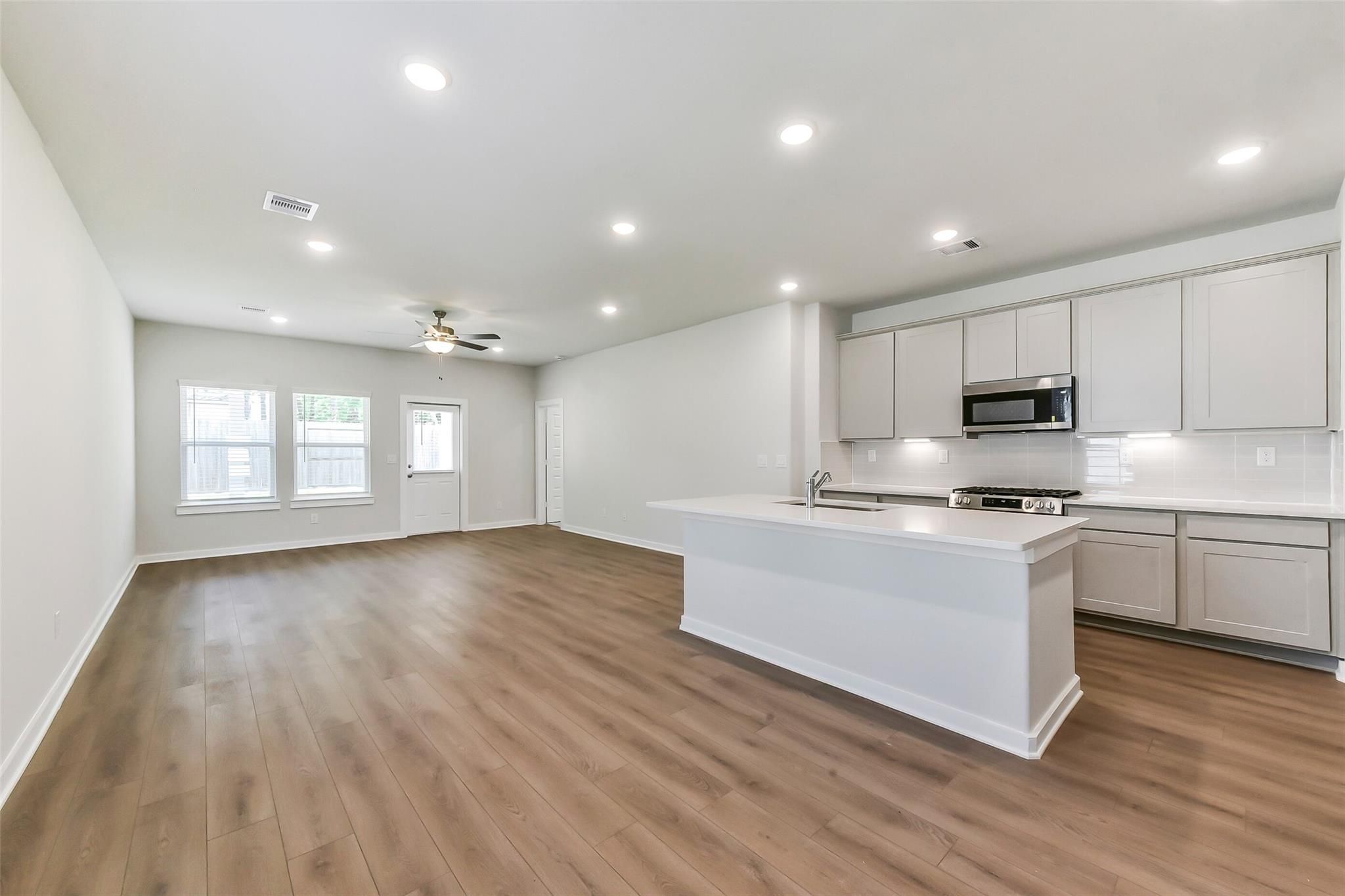 Modern open-concept kitchen with white shaker cabinets, stainless appliances, and quartz island in Davidson Homes The Brazos E, Magnolia TX