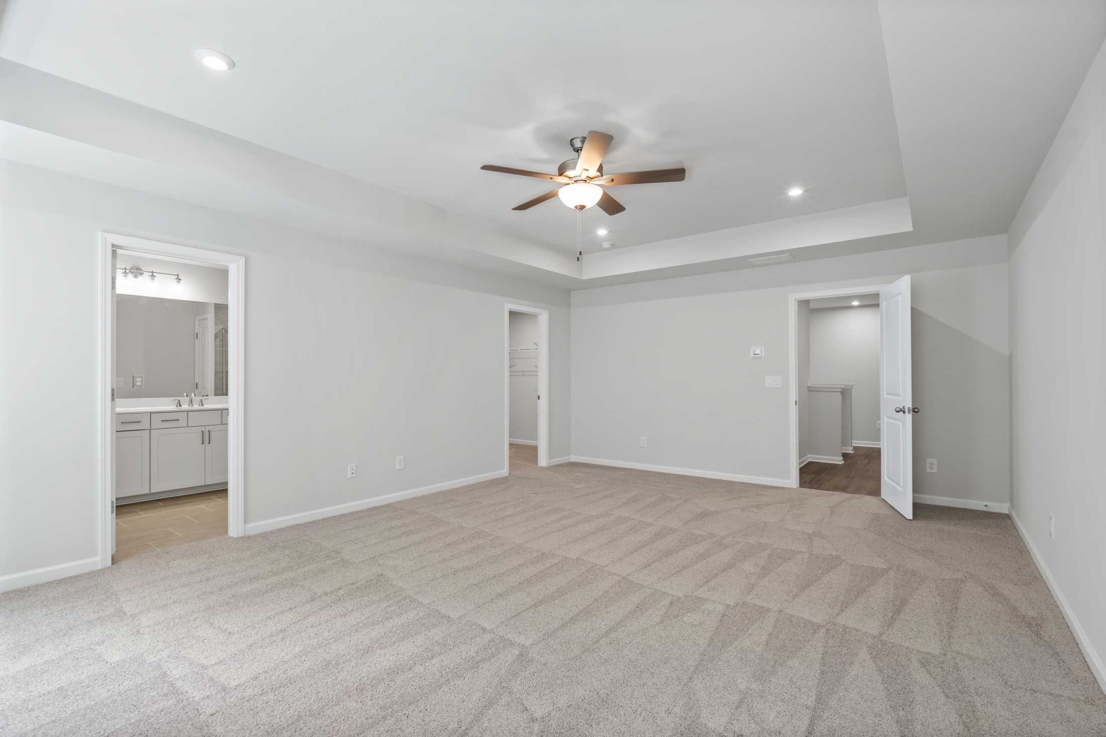 Spacious master bedroom in The Cary A featuring ceiling fan, en-suite bath with vanity, and walk-in closet