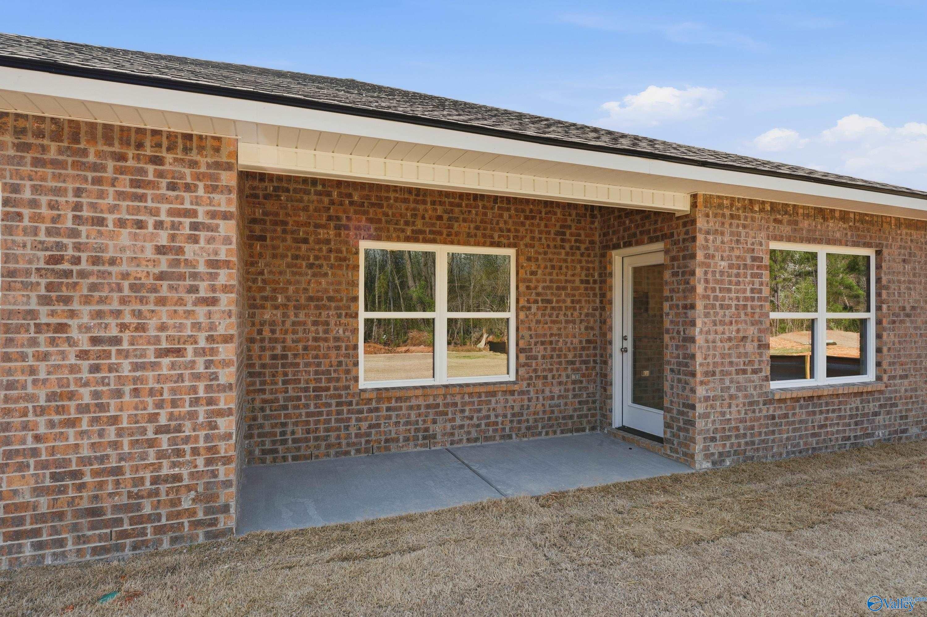 Brick single-story home exterior with covered porch, white-framed windows, and glass entry door in Spragins Cove, Huntsville, Alabama