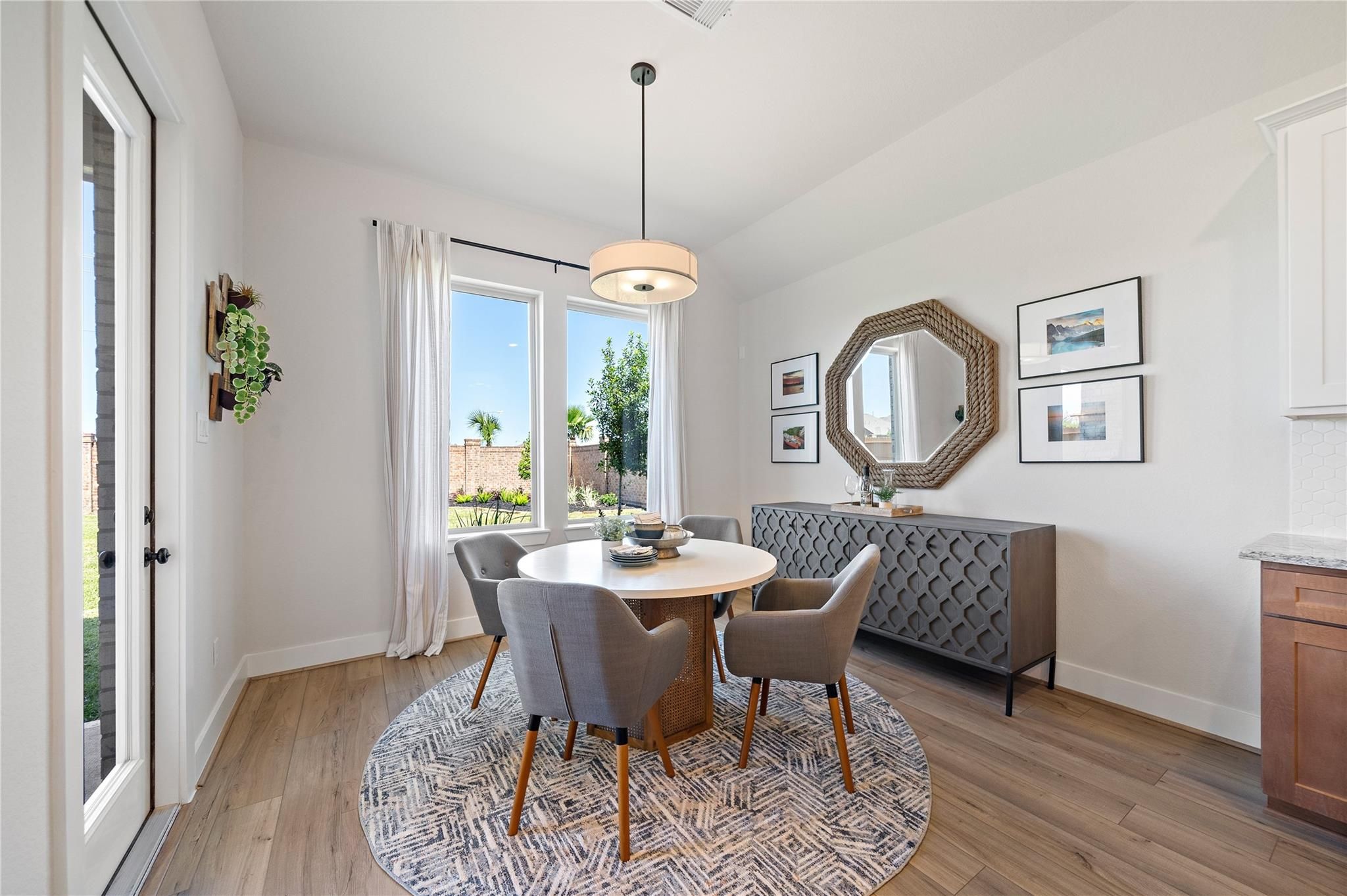 Bright breakfast nook with round dining table, gray chairs, and wood-look flooring in Davidson Homes The Edward A, Lago Mar, Texas City