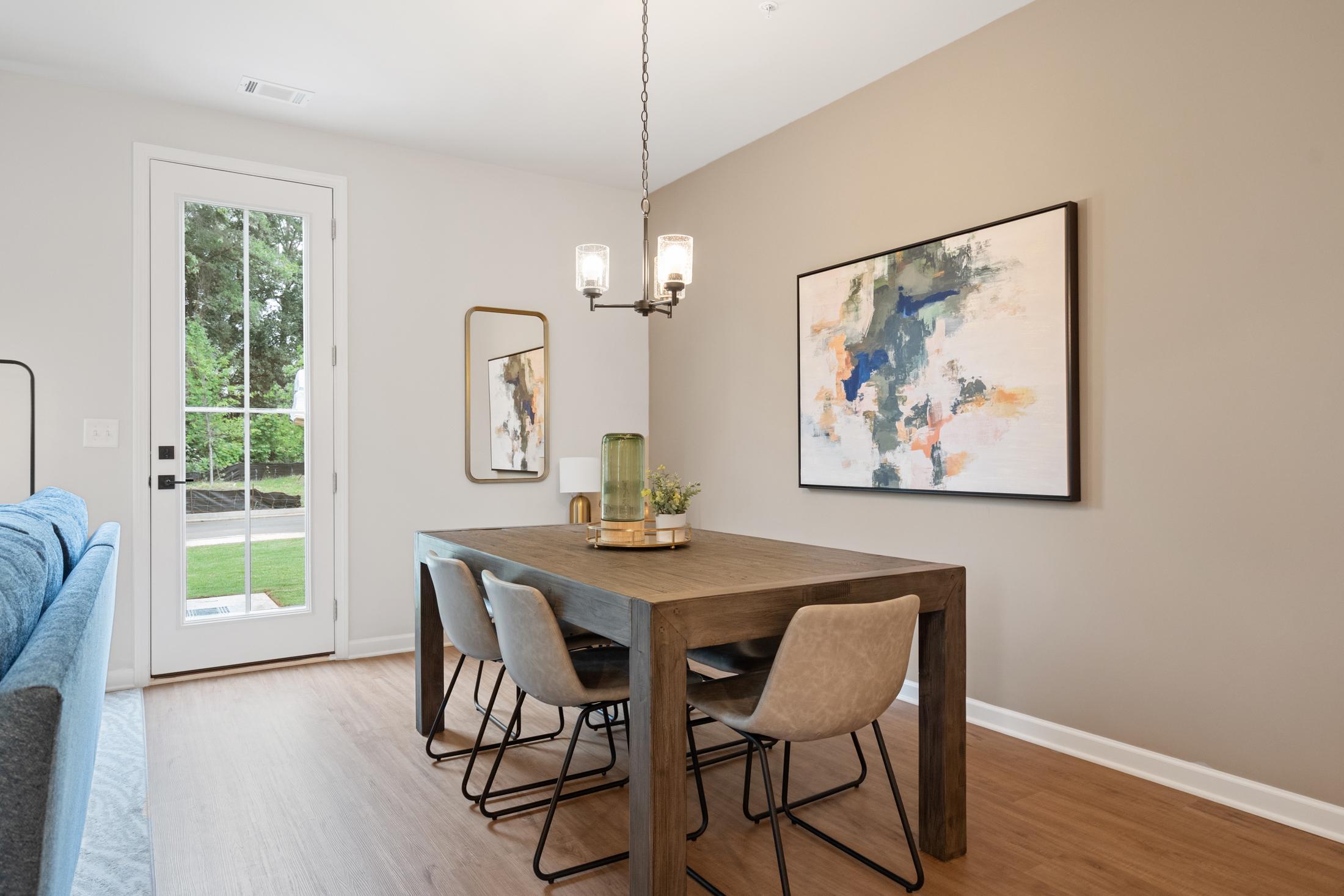 Elegant dining room at Rosehill Townhomes in Marietta GA with wooden table, upholstered chairs, chandelier, abstract art, and French doors