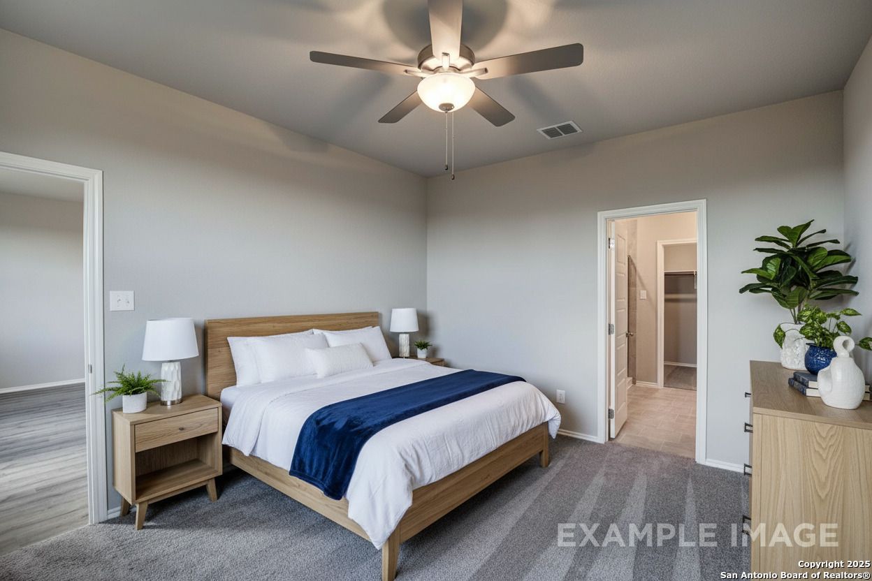 Serene master bedroom with king bed, ceiling fan, walk-in closet, and en-suite bath in Davidson Homes The Blanco C, Agave, San Antonio