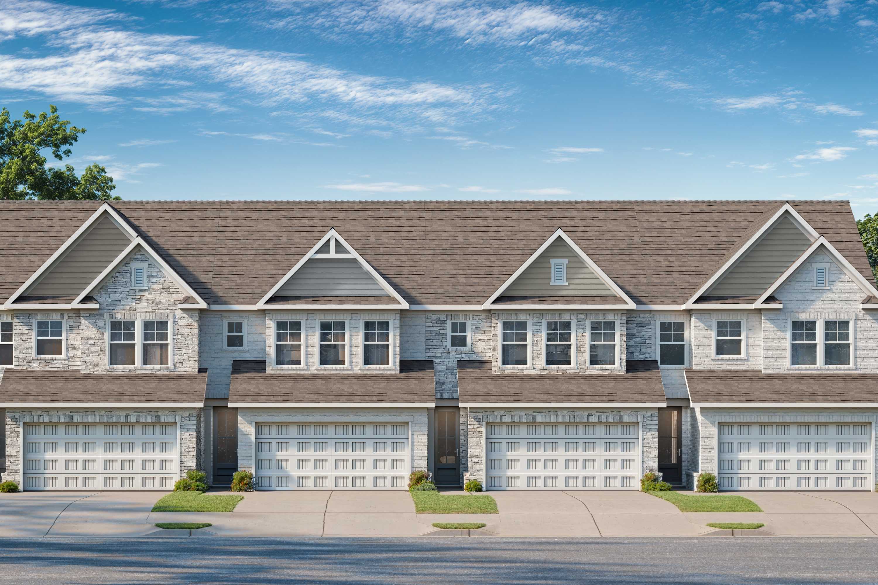 Row of modern townhomes at Lake Shore in Winder, Georgia with gabled roofs, attached garages and lush green landscaping