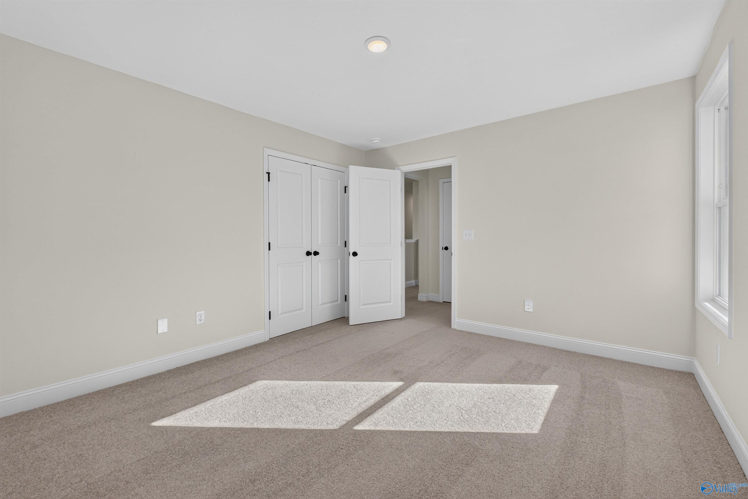 Bright bedroom with plush carpet, white double-door closet, and sunny window in Davidson Homes Ashport L, New Market, Alabama