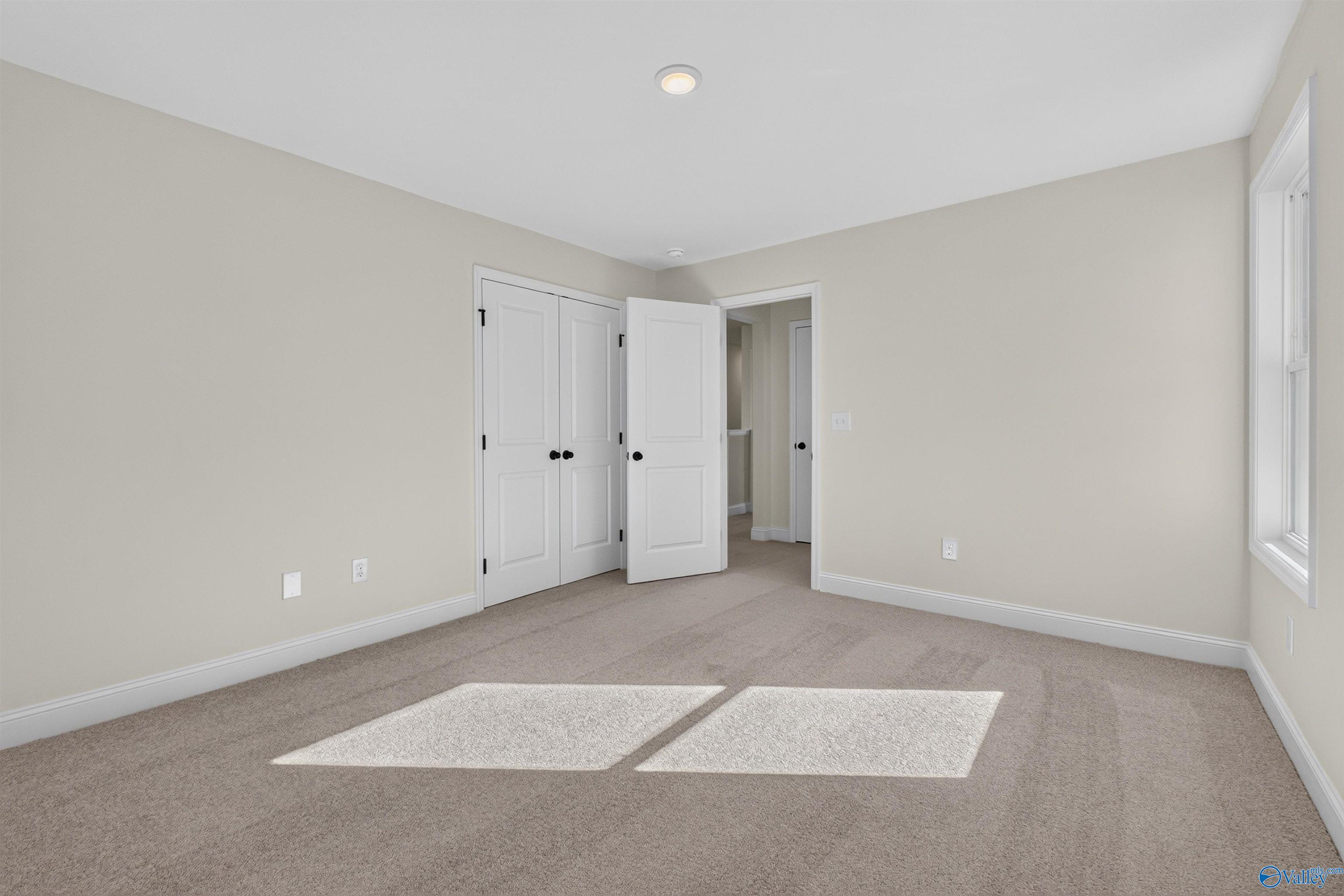 Bright bedroom with plush carpet, white double-door closet, and sunny window in Davidson Homes Ashport L, New Market, Alabama