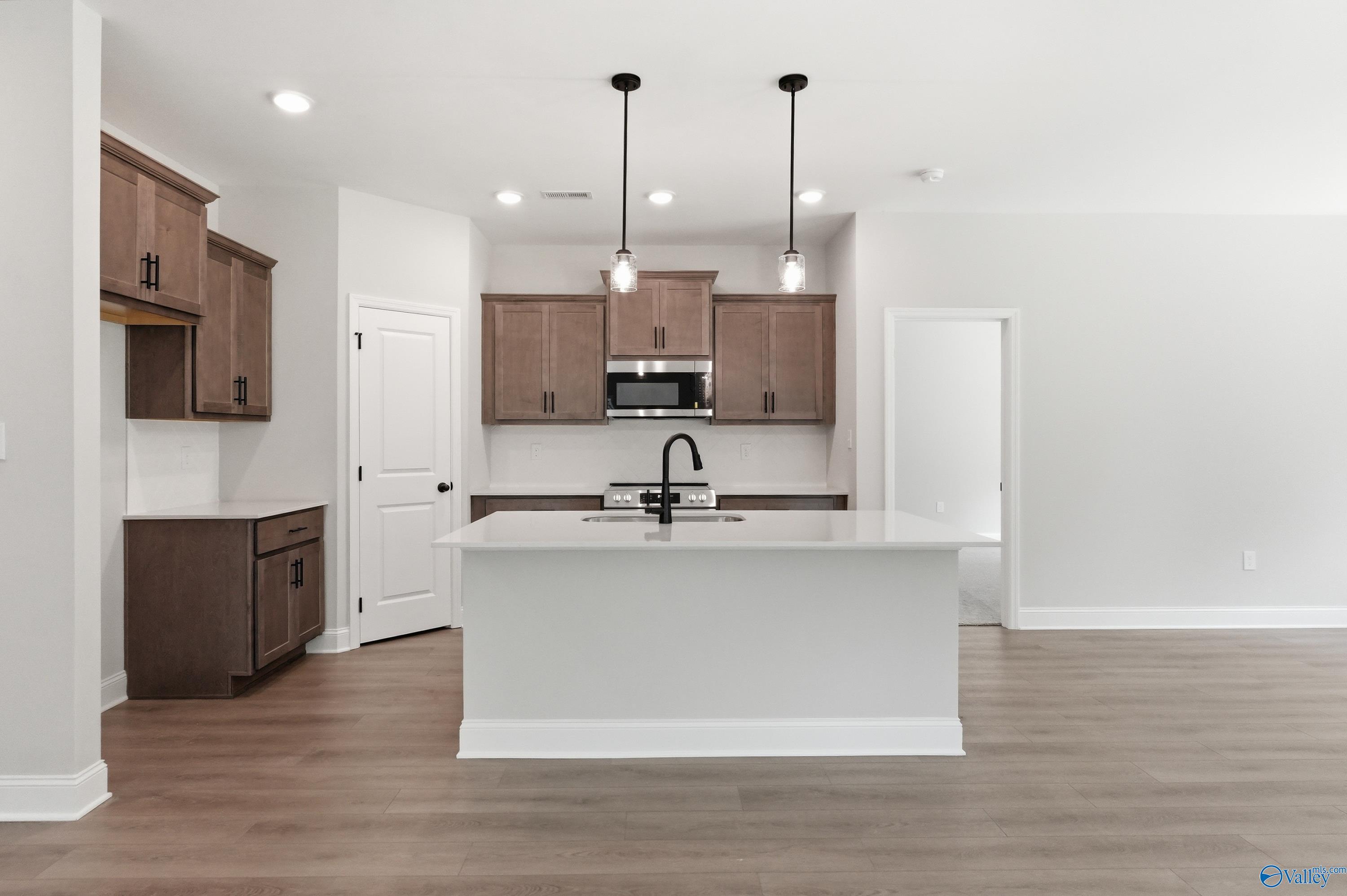 Modern kitchen featuring white island, shaker cabinets, stainless steel appliances, and pendant lights in The Franklin by Davidson Homes, Huntsville