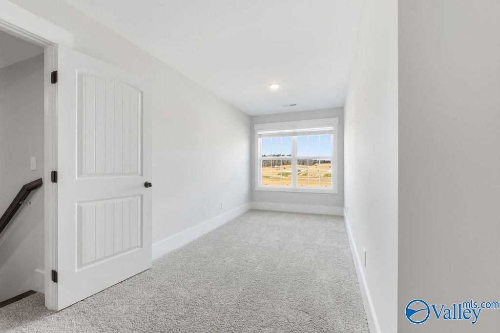 Bright upstairs bedroom with large window and gray carpet in Davidson Homes The Rockford, Hartselle, Alabama