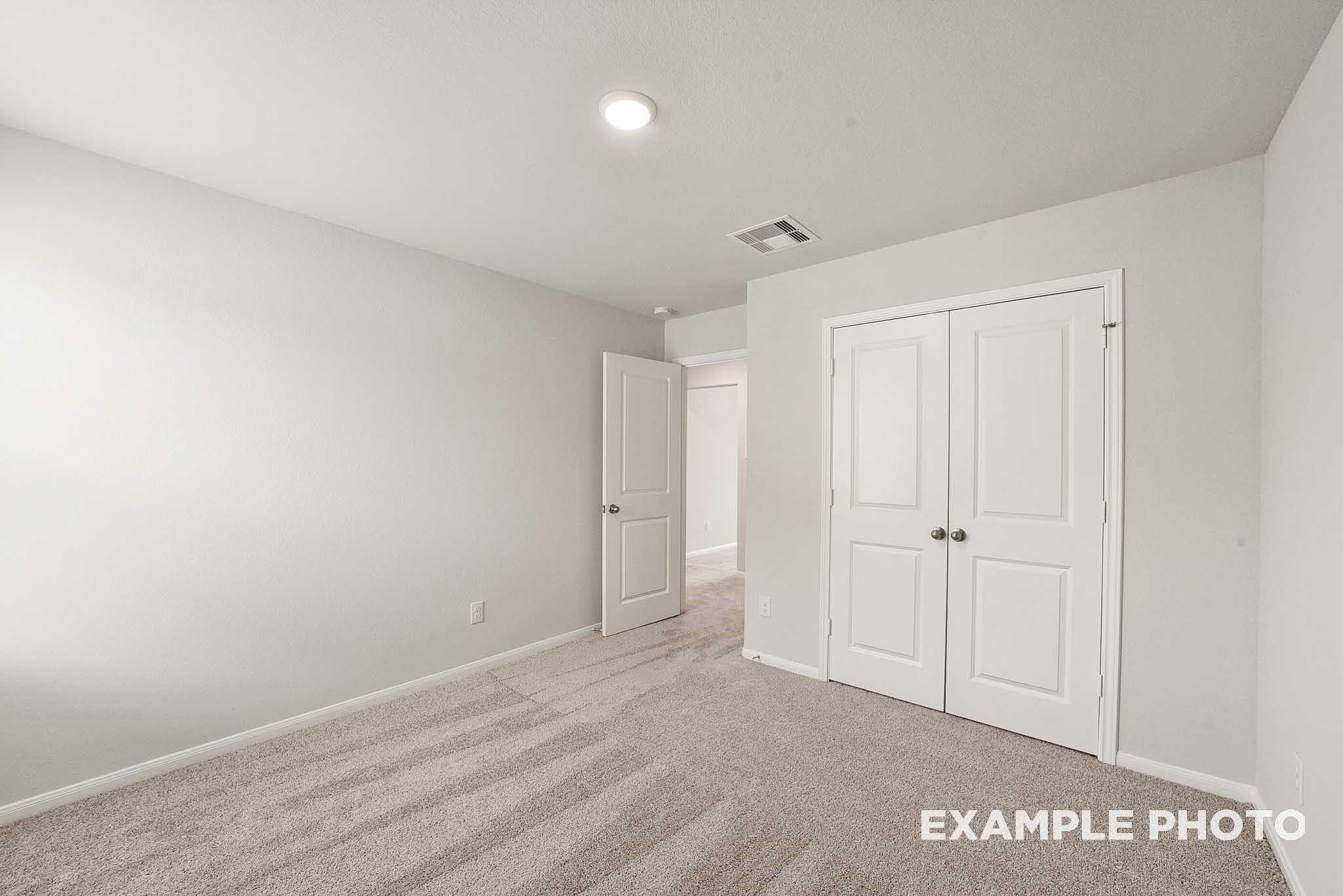 Spacious secondary bedroom with double-door closet, beige carpet, and gray walls in Davidson Homes Tierra B, Beasley, Texas