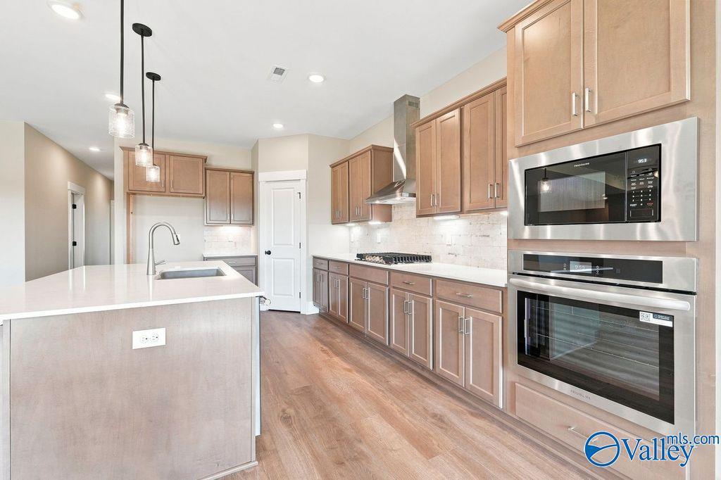 Modern kitchen with wood cabinets, center island, and stainless steel appliances in The Rockford plan, Cain Park, Hartselle.