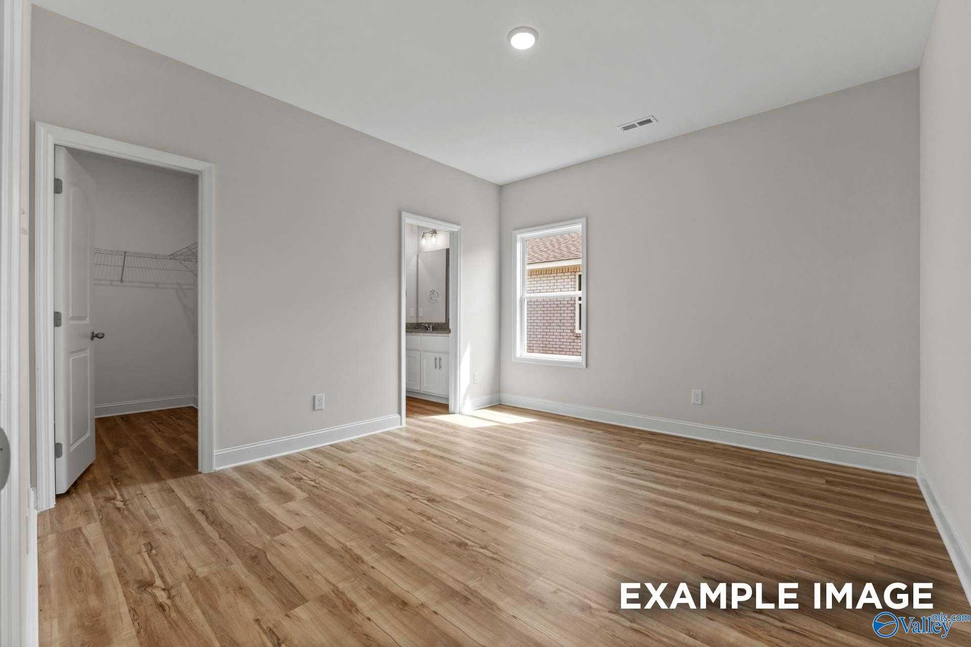 Bright bedroom with hardwood floors, walk-in closet, and en-suite bath in Davidson Homes The Butler, Toney, Alabama