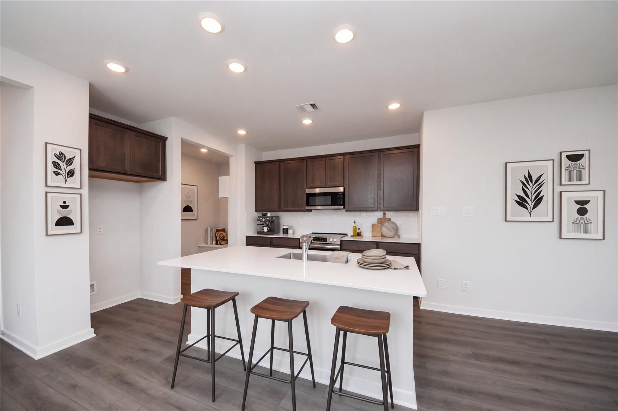 Modern kitchen with white island, dark wood cabinets, and bar seating in Davidson Homes The Brazos F, Cleveland, Texas