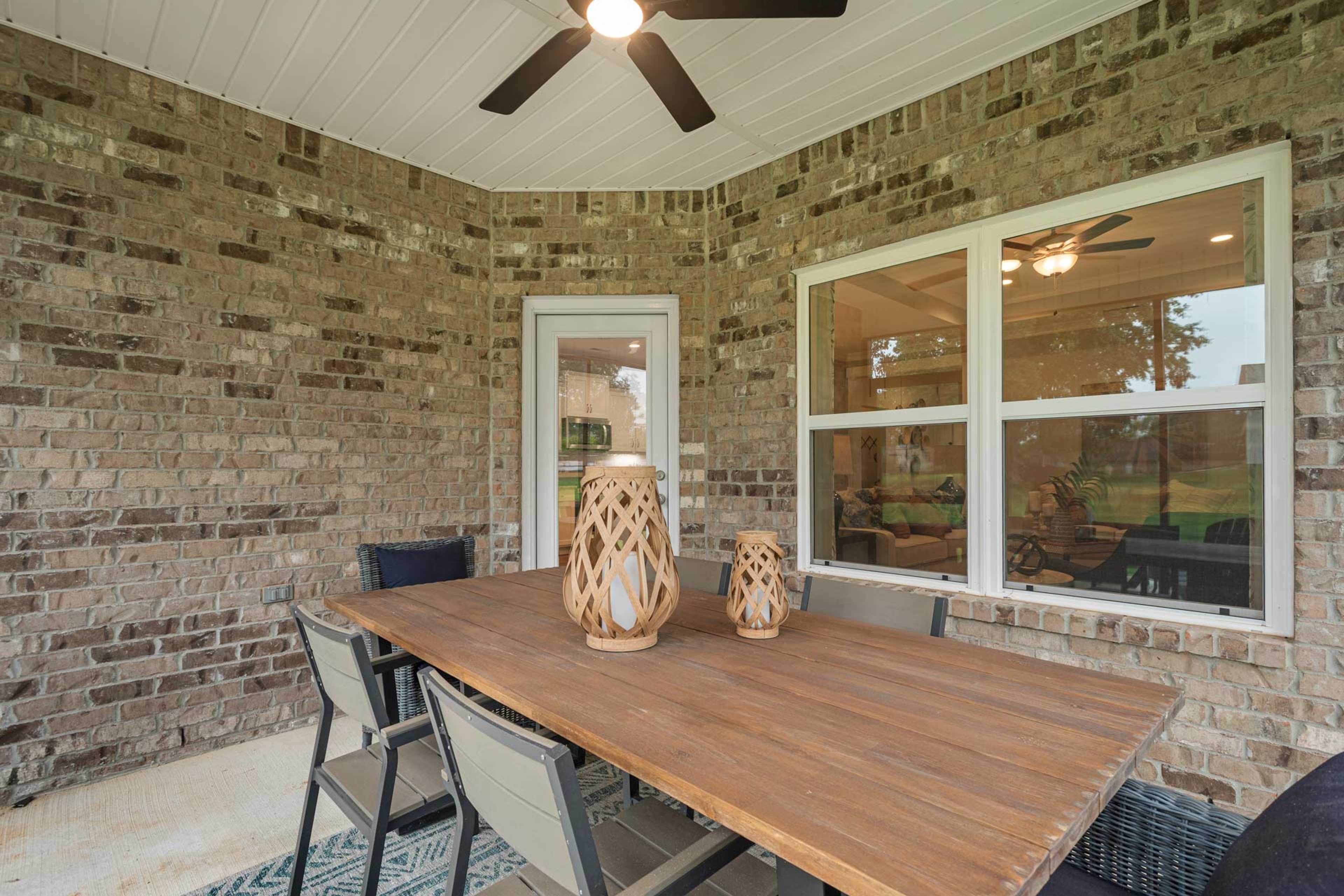 Covered patio at Monteagle Cove in Owens Cross Roads Alabama featuring teak dining table brick walls large windows and ceiling fan