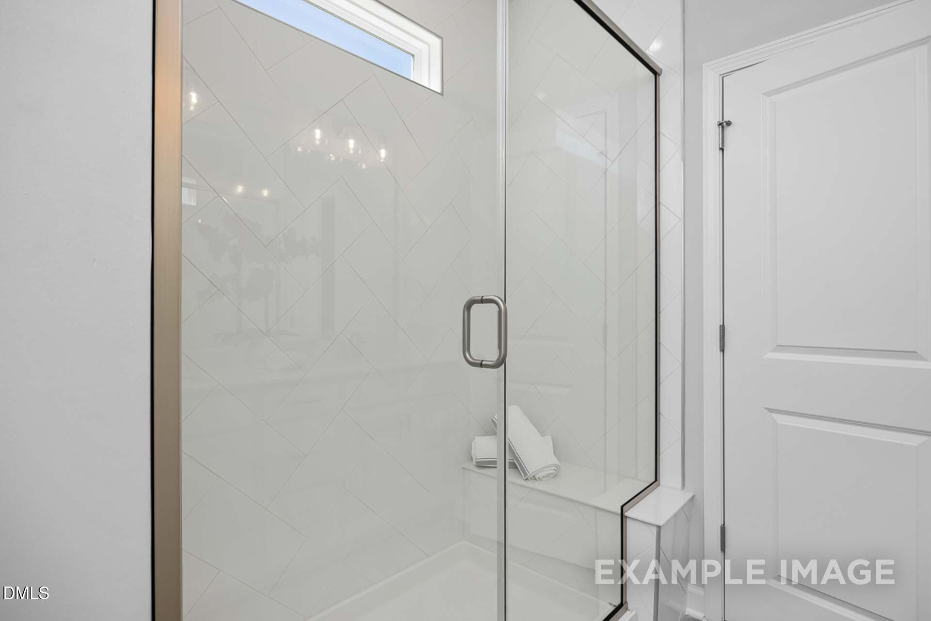 Modern frameless glass shower with subway tiles, bench seat, and window in The Carter C master bath, Davidson Homes, Lillington, NC