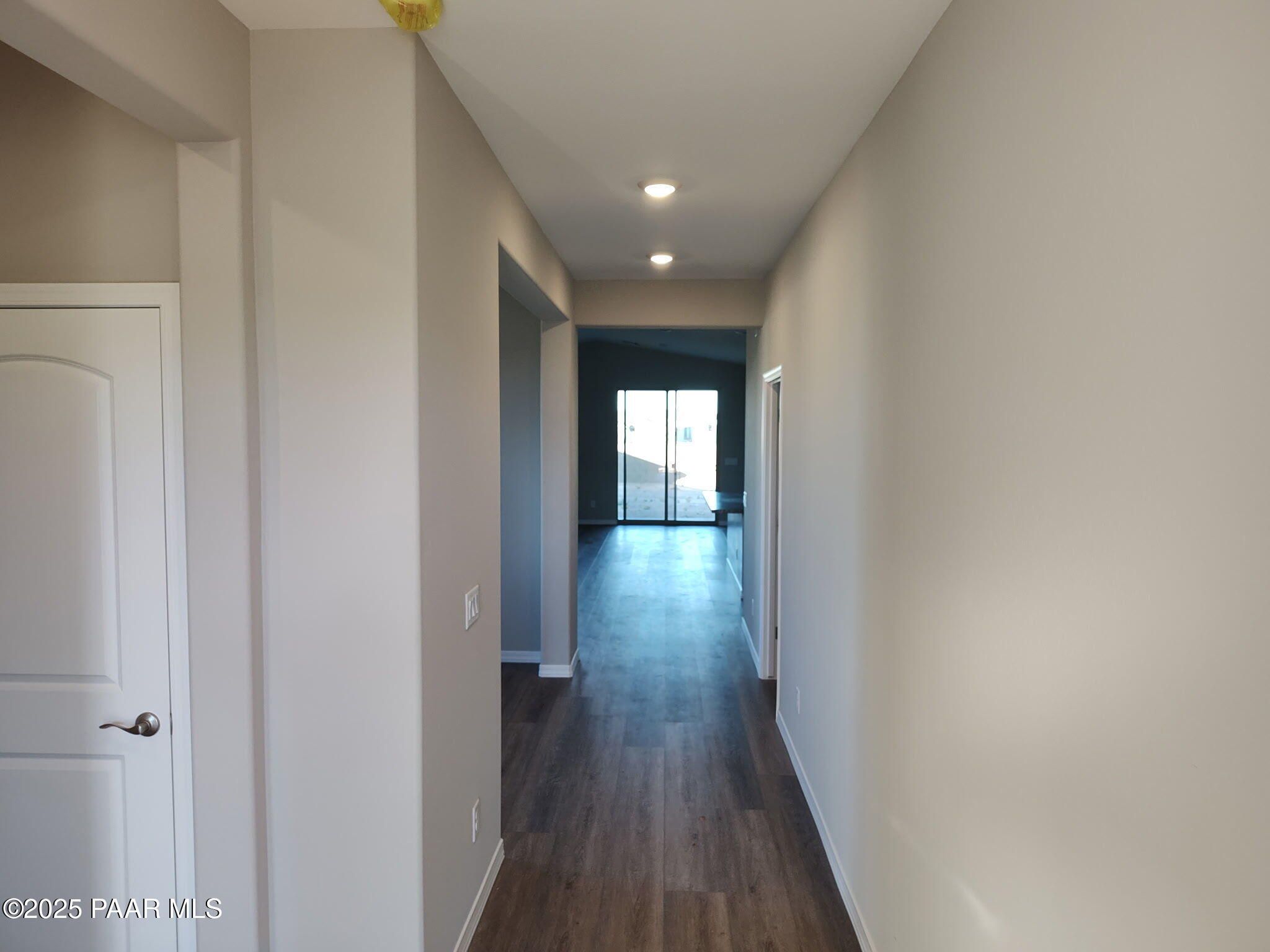 Long hallway with hardwood floors, beige walls, and recessed lights leading to sliding glass doors in Davidson Homes The Frontier A, Prescott Valley, Arizona