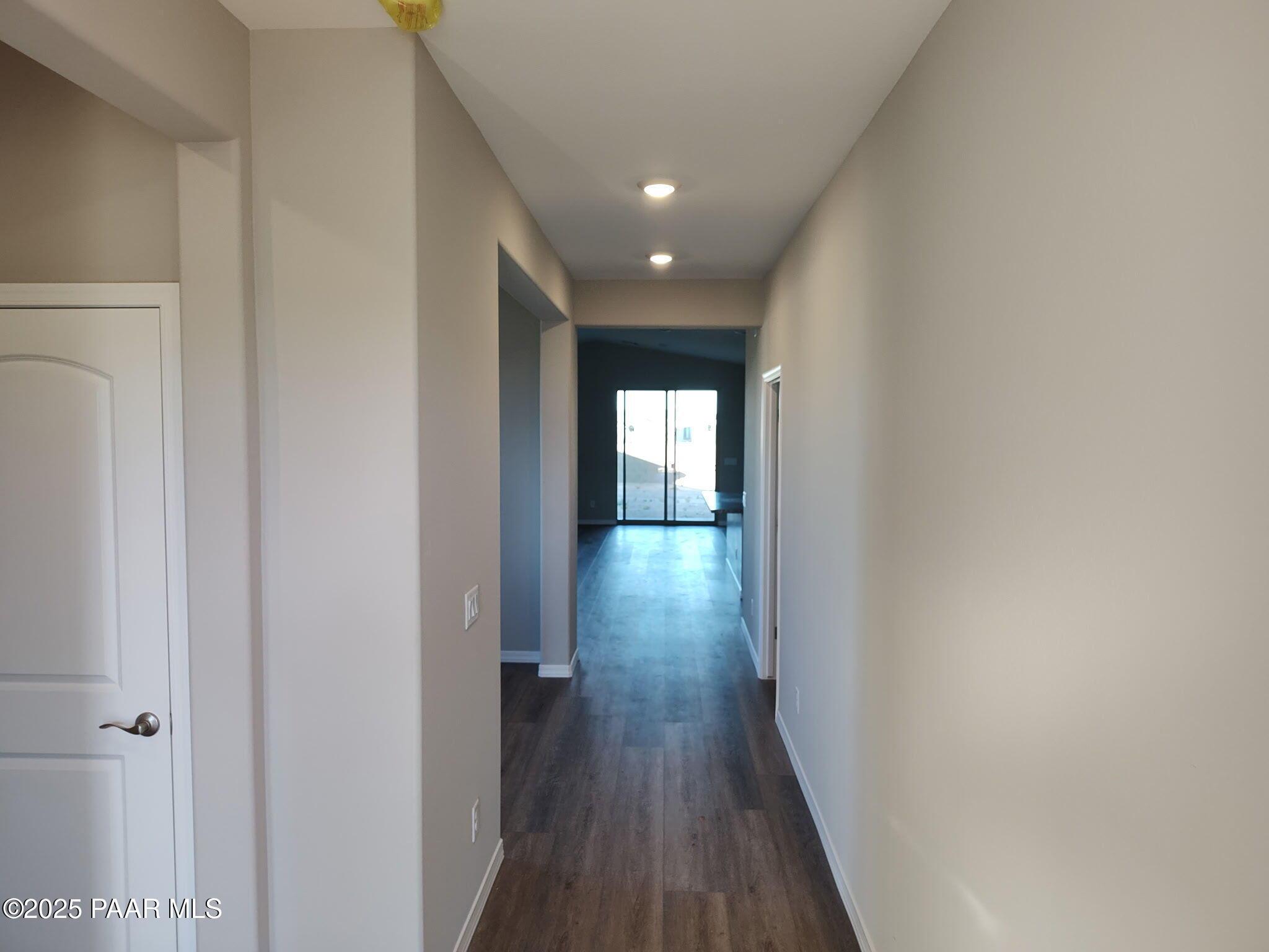 Long hallway with hardwood floors, beige walls, and recessed lights leading to sliding glass doors in Davidson Homes The Frontier A, Prescott Valley, Arizona