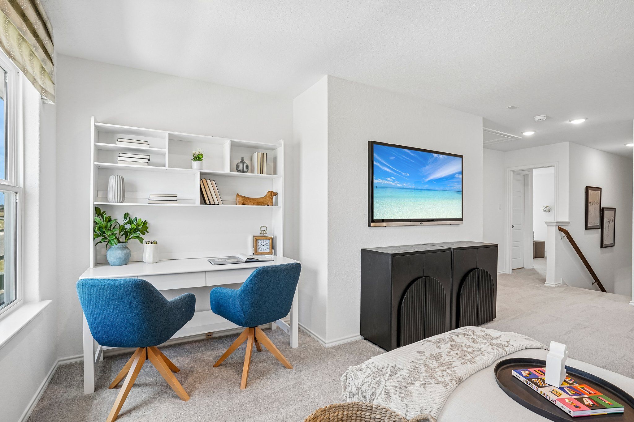 Home office space at Morgan Meadows in San Antonio with white desk, blue chairs, and wall-mounted TV by Davidson Homes.