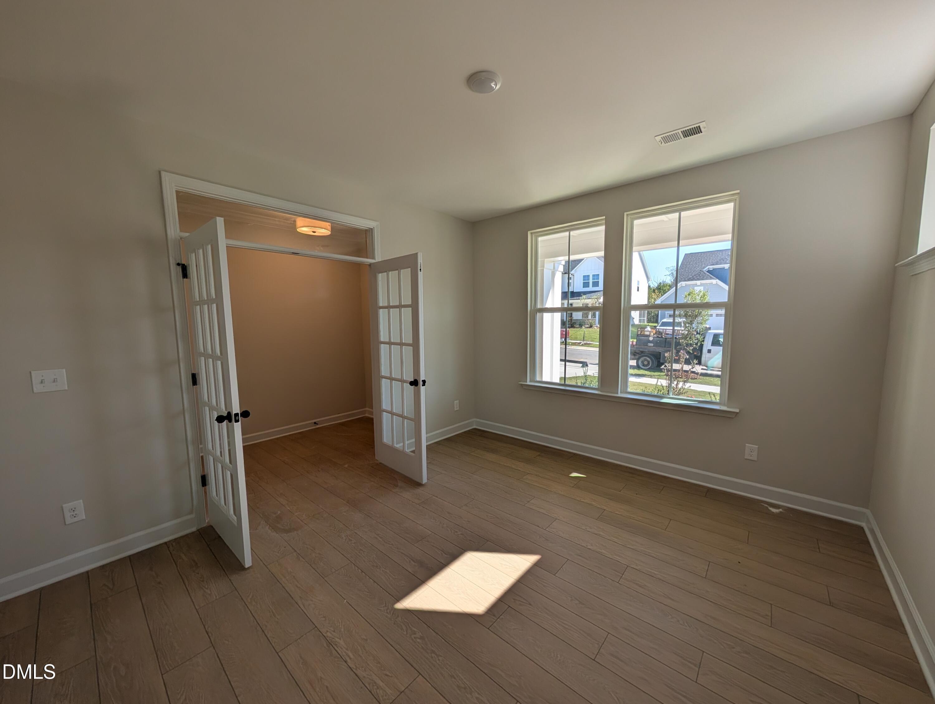 Bright flexible room with French doors, wood-look flooring, and large windows in Davidson Homes The Ashport M, Wendell Ridge, NC