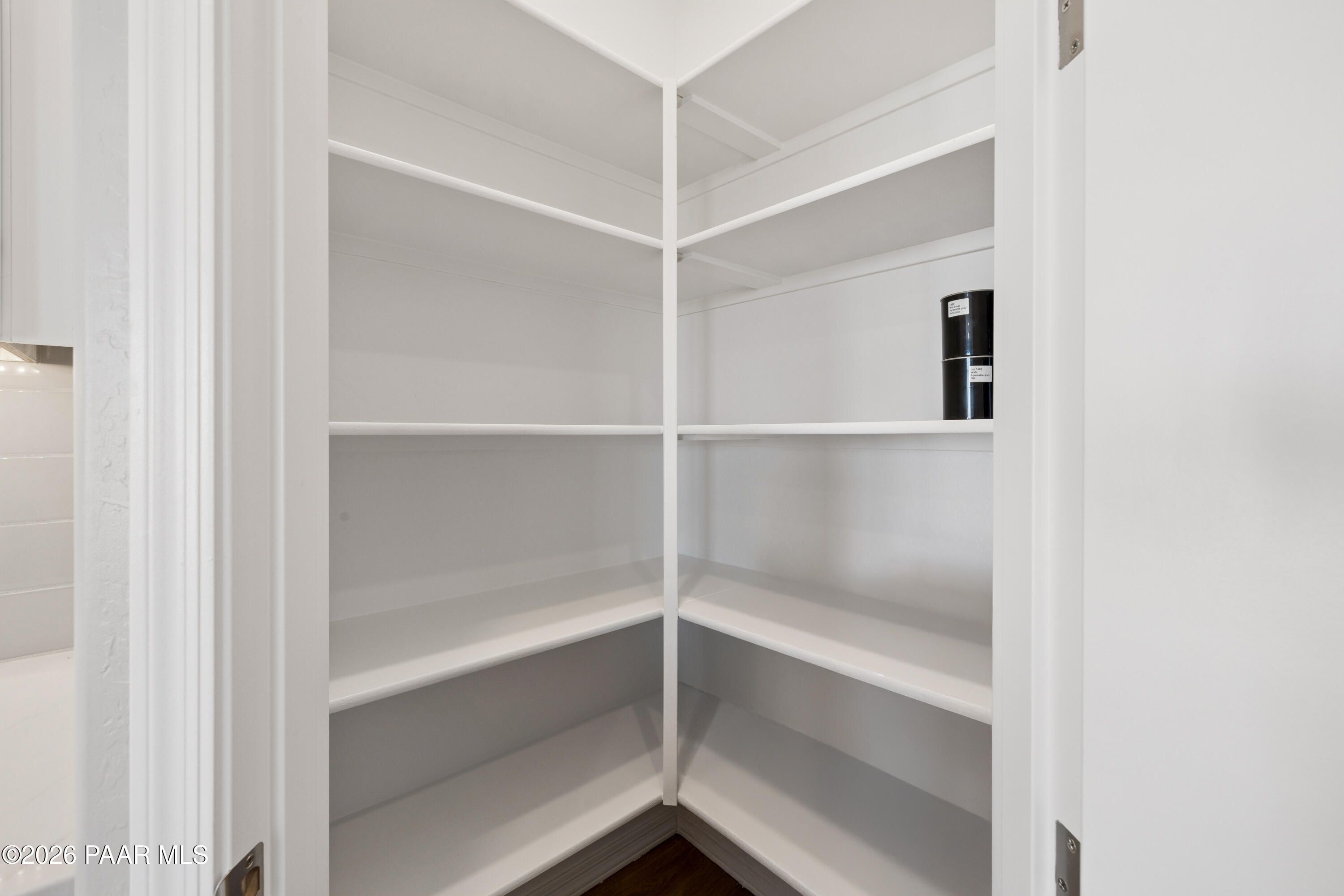 Spacious corner walk-in pantry with white wooden shelves in The Harmony A floor plan, Davidson Homes, Prescott Valley, Arizona