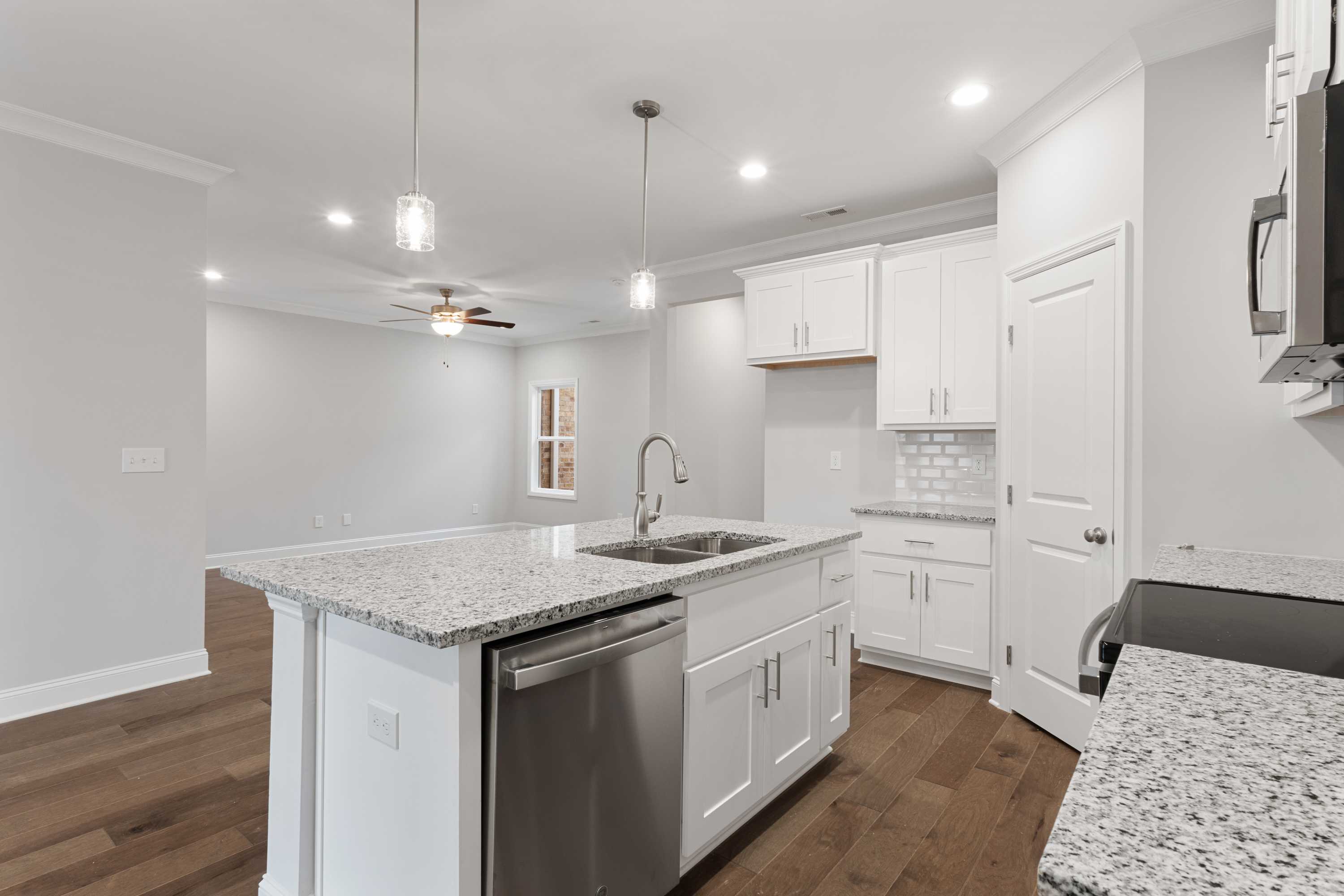 Modern kitchen in The Copeland B with white shaker cabinets, granite island sink, stainless appliances, and open layout