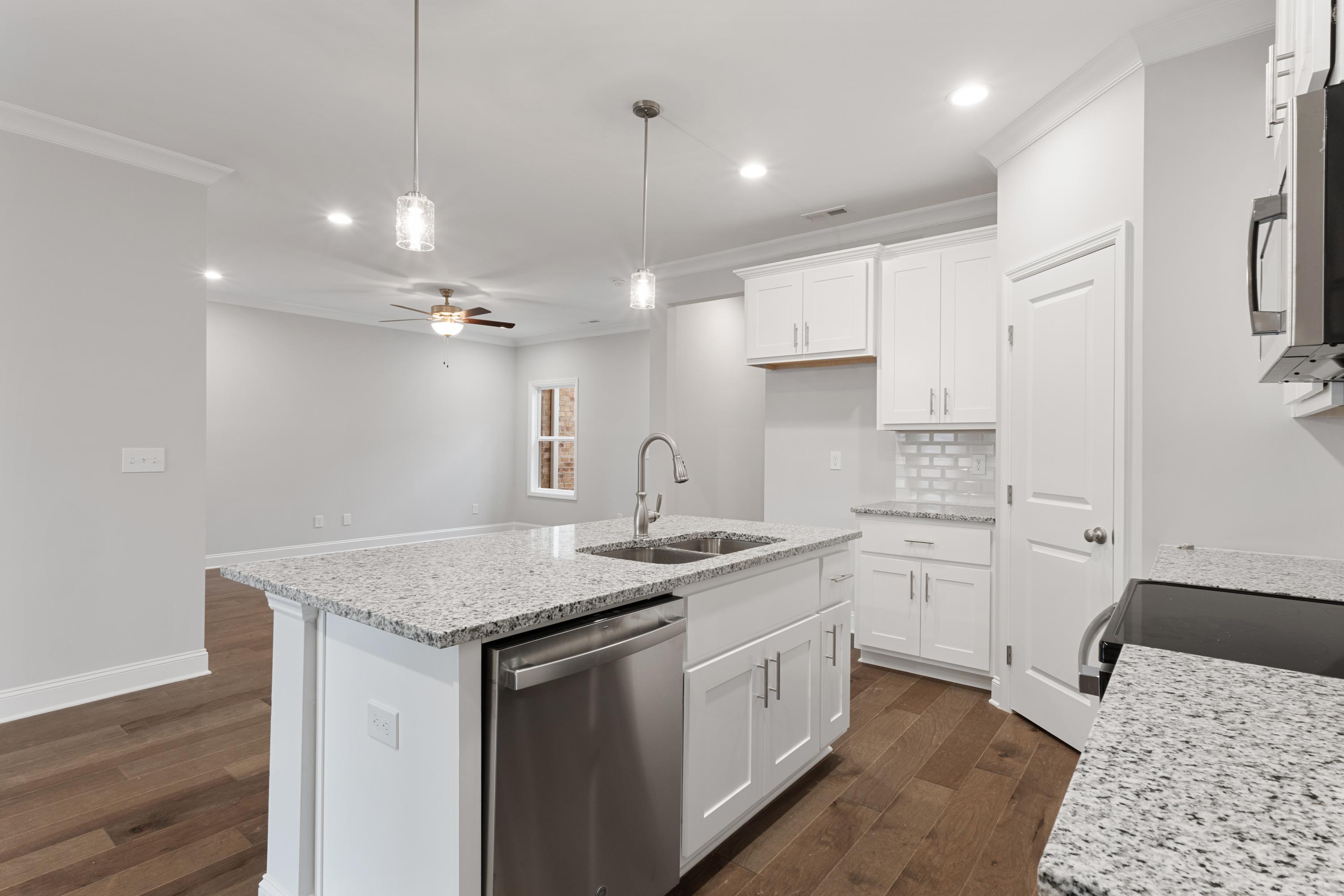Modern Copeland C kitchen with white cabinets, granite island sink, stainless dishwasher, open to living area, hardwood floors