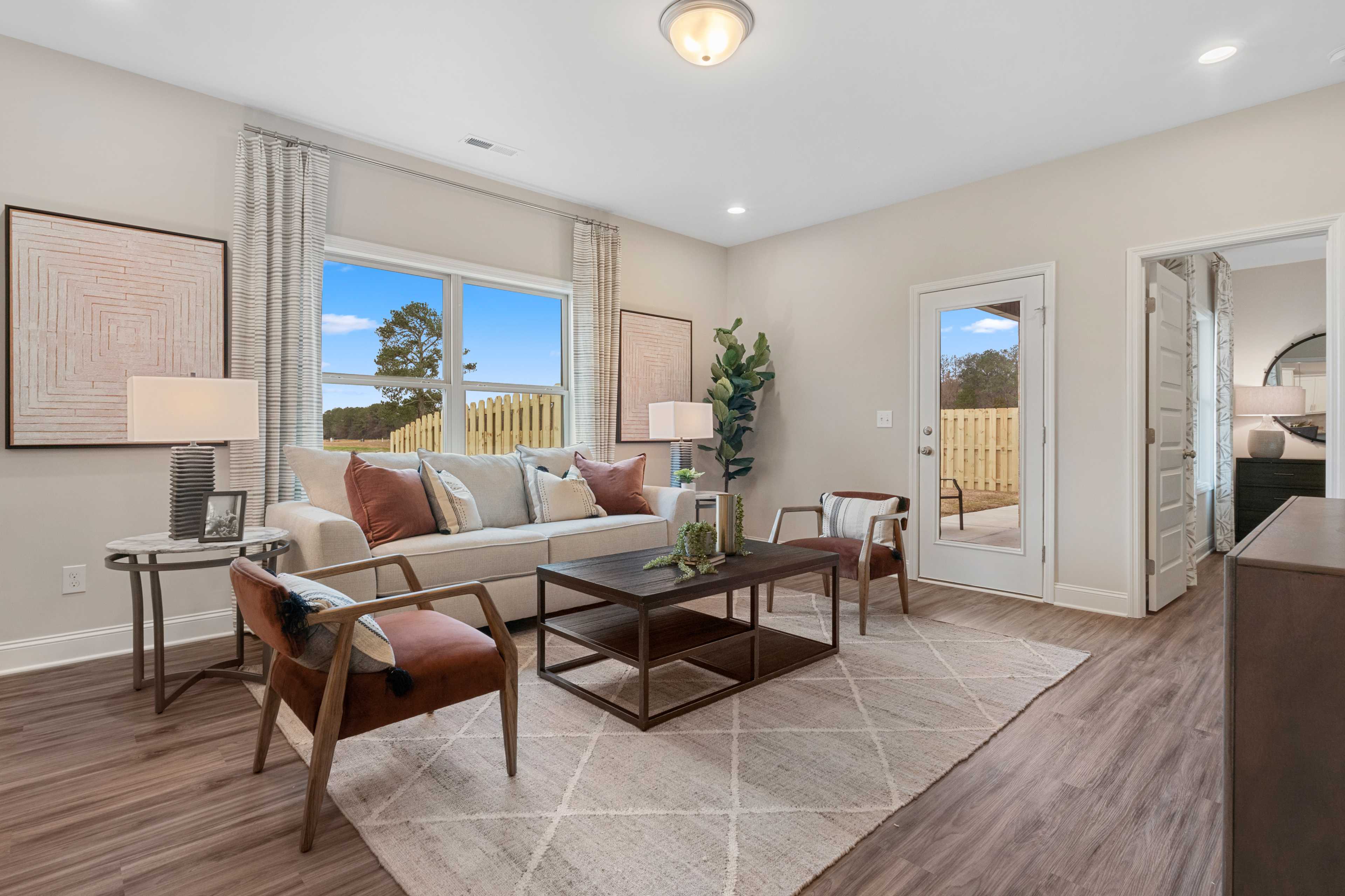 Spacious living room at The Retreat at Cain Park in Hartselle AL with beige sofa, hardwood floors, large windows and neutral decor