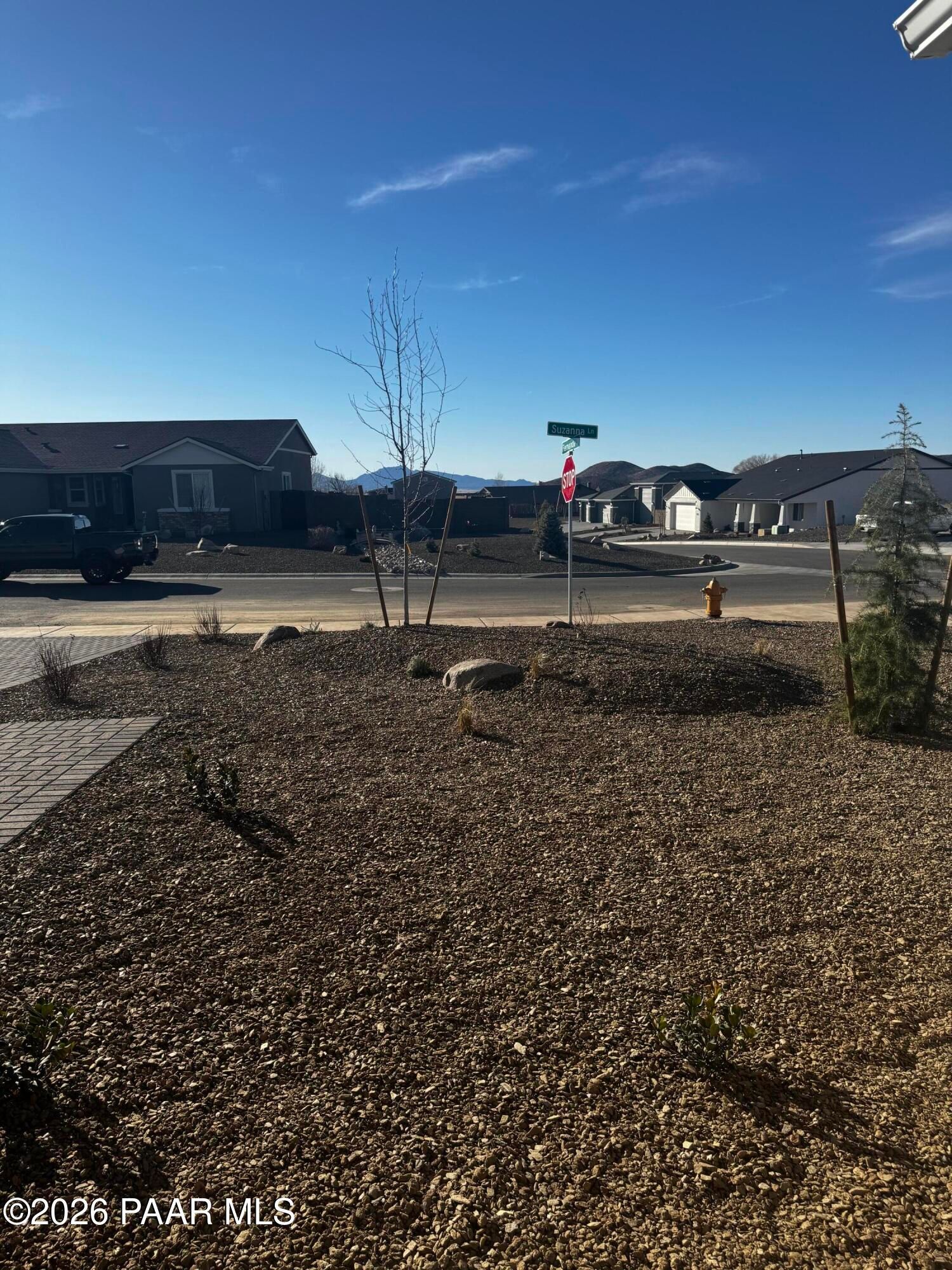 Street view of gravel landscaped lot with young trees and stop sign in Morningstar, Prescott Valley, Arizona 3-bedroom home community
